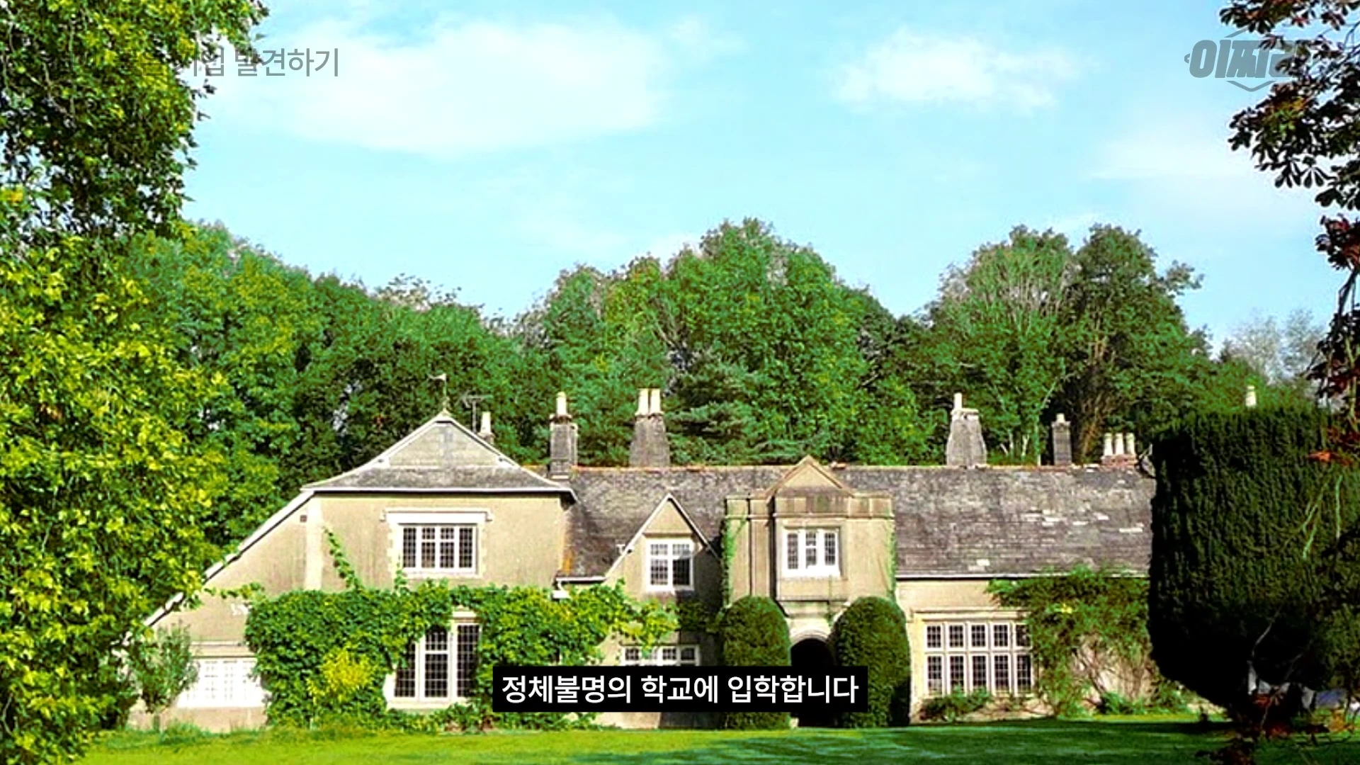 푸른 나무와 넓은 잔디밭으로 둘러싸인 고풍스러운 영국식 저택 건물이 보입니다.