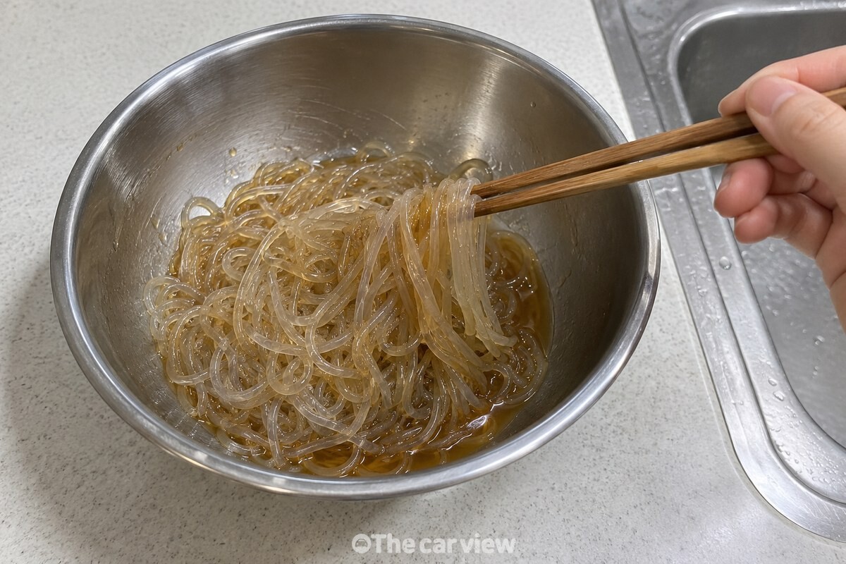 삶아 낸 당면에 간장과 사과즙 양념을 고르게 버무리고 있다. / 기사 이해를 돕기 위한 생성형 이미지