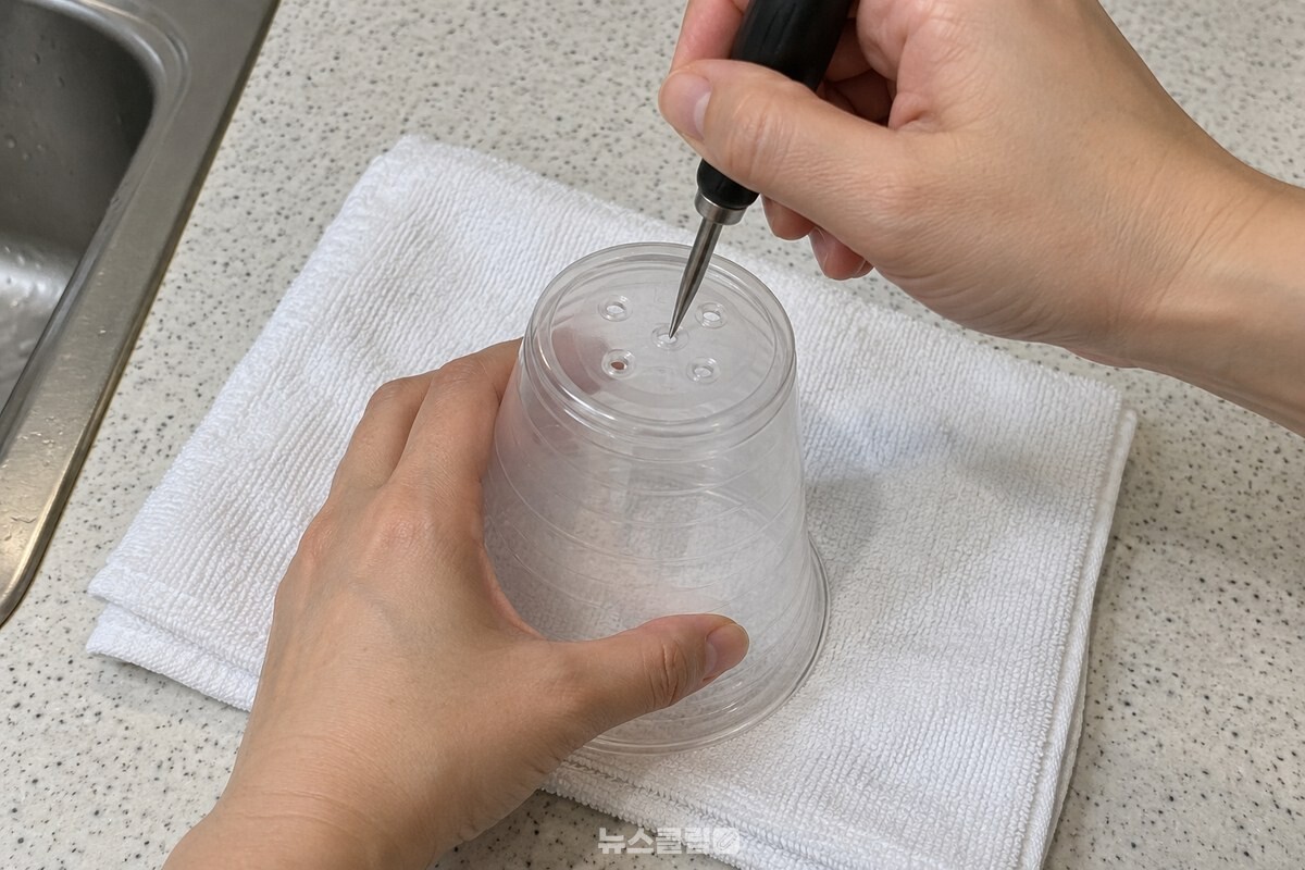 접은 수건 위에 뒤집어 놓은 컵 바닥에 작은 구멍을 뚫는 손. / 기사 이해를 돕기 위한 생성형 이미지