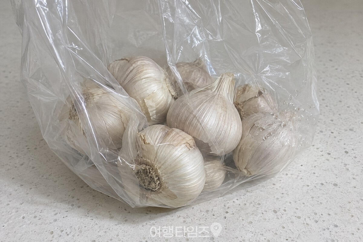 투명 비닐봉지 안쪽에 작은 물방울이 맺히고 통마늘이 바닥에 놓여 있다. / 기사 이해를 돕기 위한 생성형 이미지