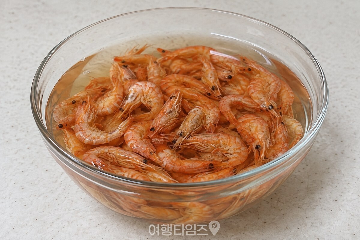 찬물에 불린 작은 건새우와 옅은 갈색을 띤 불린 물을 담은 유리 볼. / 기사 이해를 돕기 위한 생성형 이미지