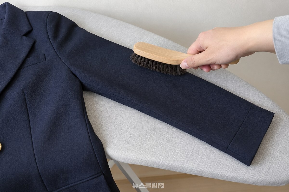 식힌 교복 소매를 어깨 쪽에서 소매 끝 방향으로 옷솔로 가볍게 쓸어 주는 모습. / 기사 이해를 돕기 위한 생성형 이미지