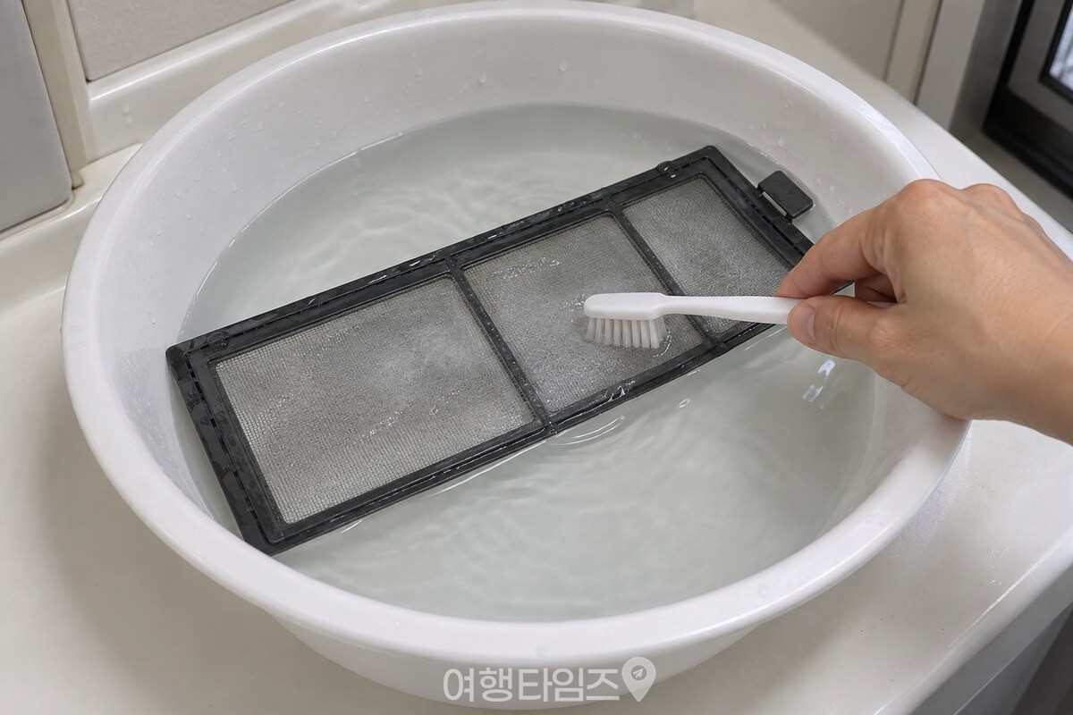 미지근한 물에 담긴 필터의 그물망을 부드러운 칫솔로 가볍게 문지르고 있다. / 기사 이해를 돕기 위한 생성형 이미지