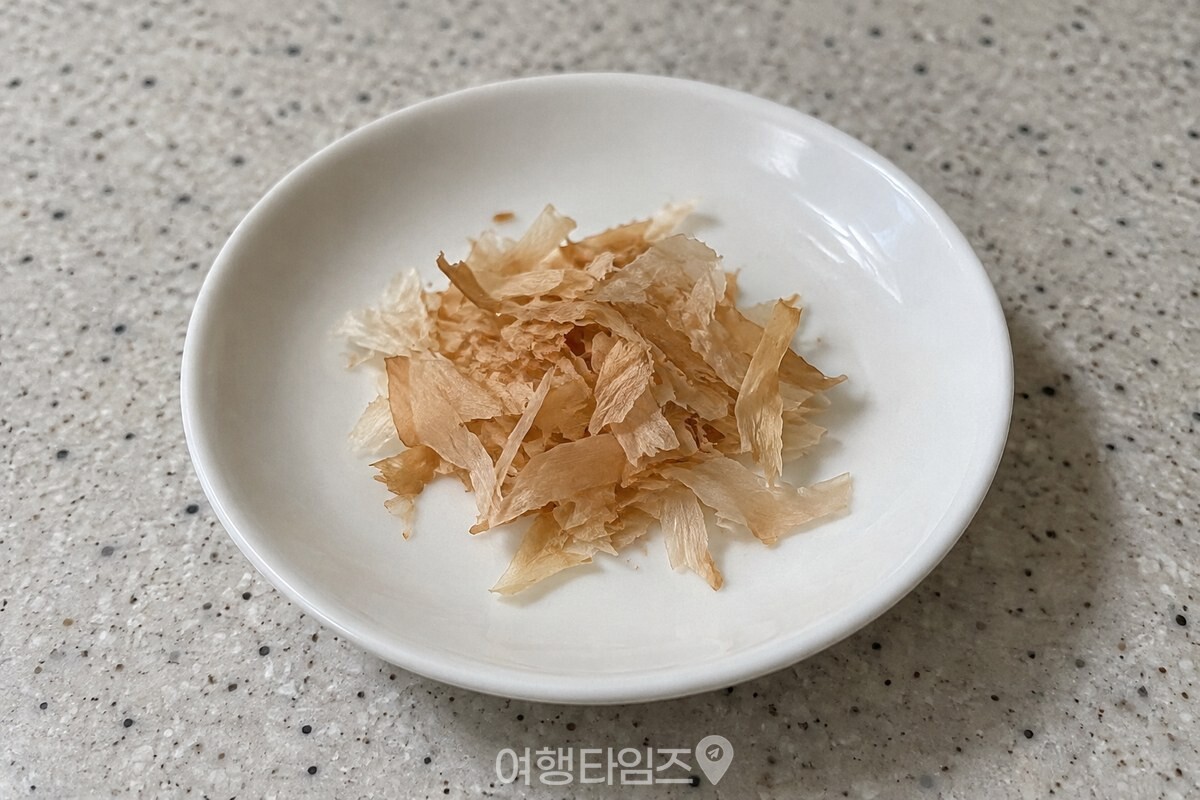 깨끗한 작은 접시에 한 꼬집 덜어 놓은 종이처럼 얇은 가쓰오부시 / 기사 이해를 돕기 위한 생성형 이미지