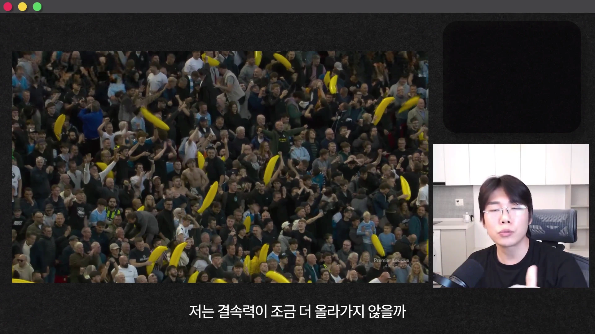 축구 경기장에서 노란 풍선을 들고 환호하는 관중들과 오른쪽 하단에 앉아 이야기하는 안경 쓴 남성