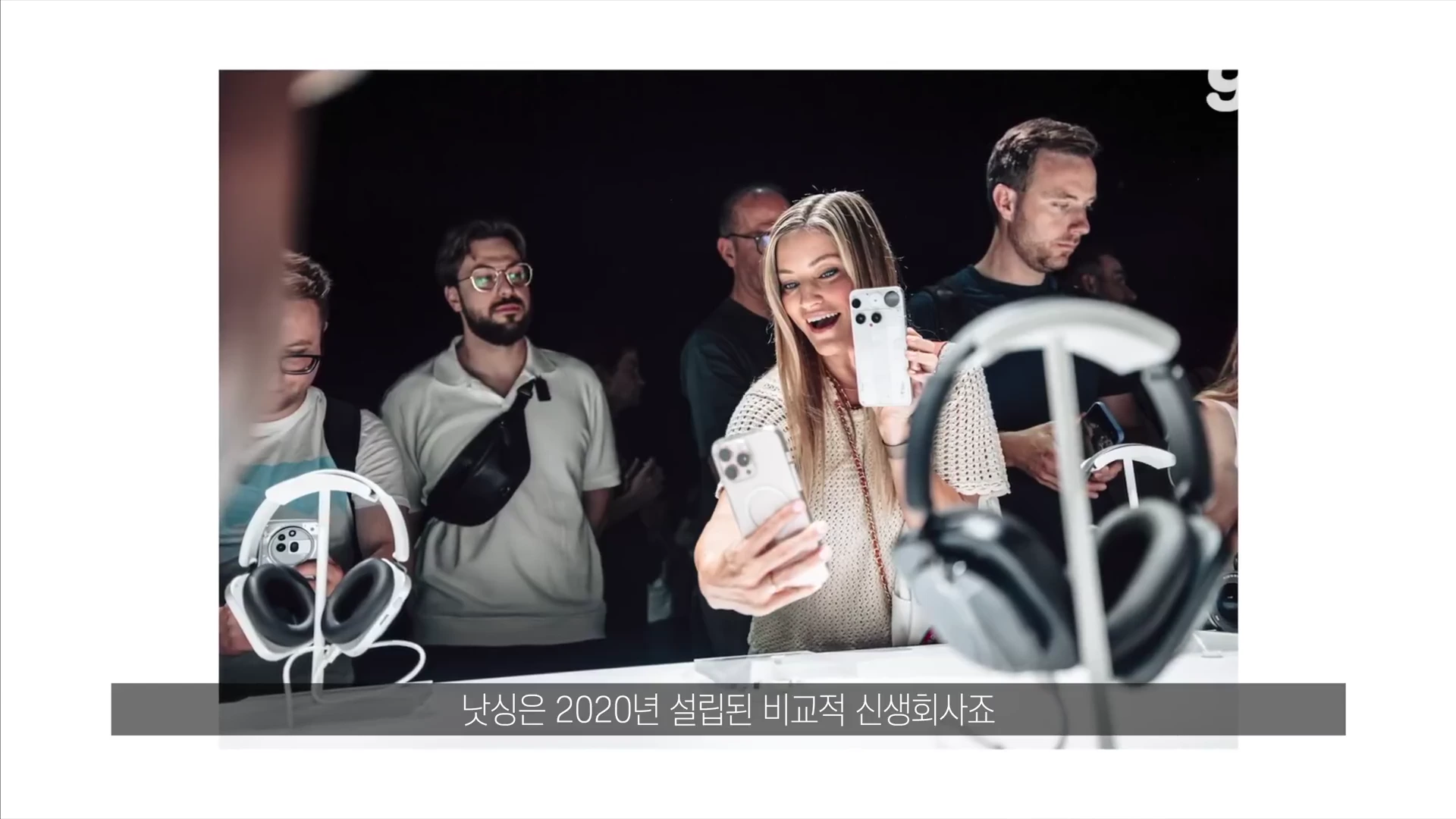 전시된 헤드폰들을 구경하는 사람들 사이에서 한 여성이 스마트폰으로 제품을 촬영하고 있는 모습