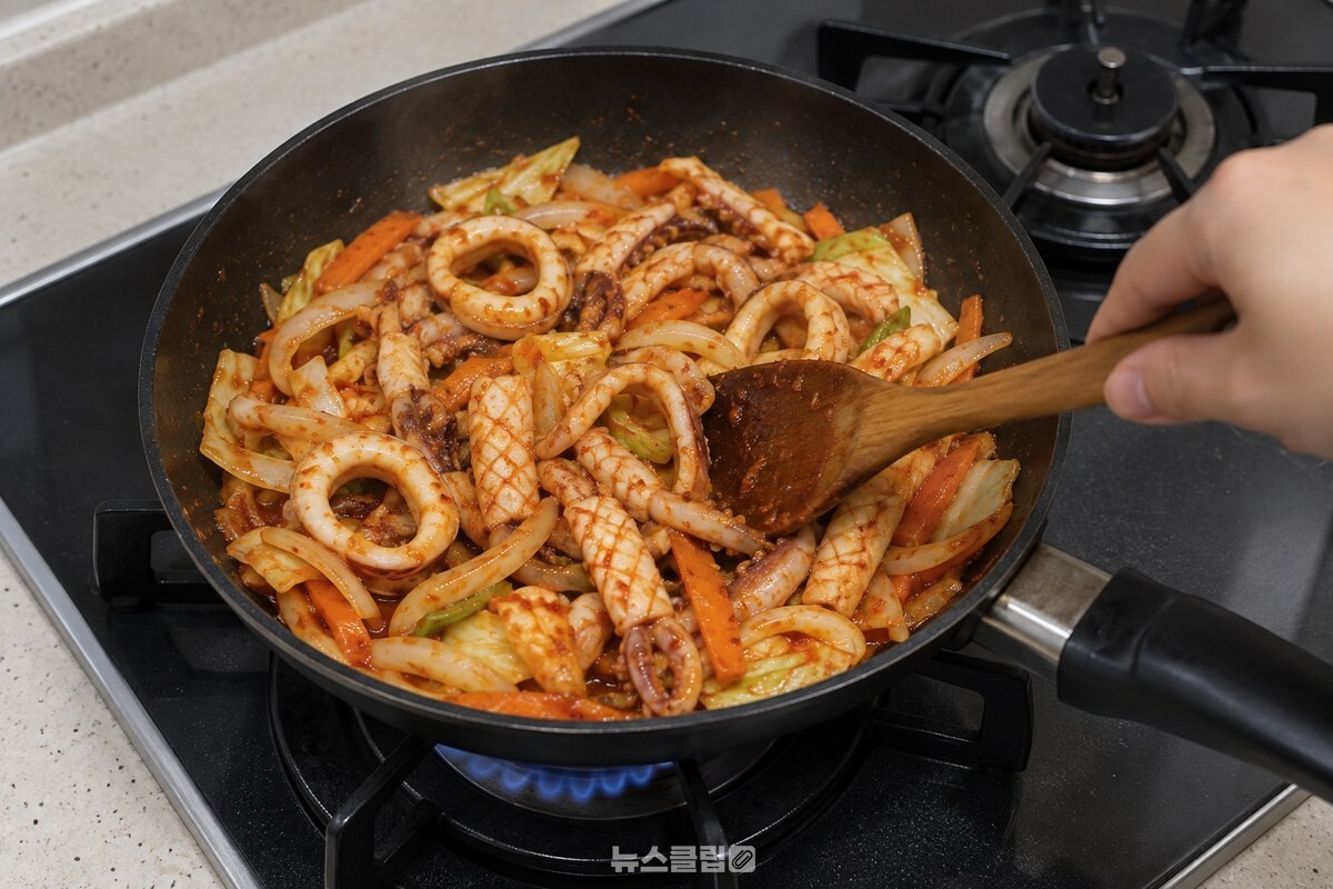 센 불의 프라이팬에서 오징어 살이 말려 올라가며 채소와 함께 익고 있다. / 기사 이해를 돕기 위한 생성형 이미지