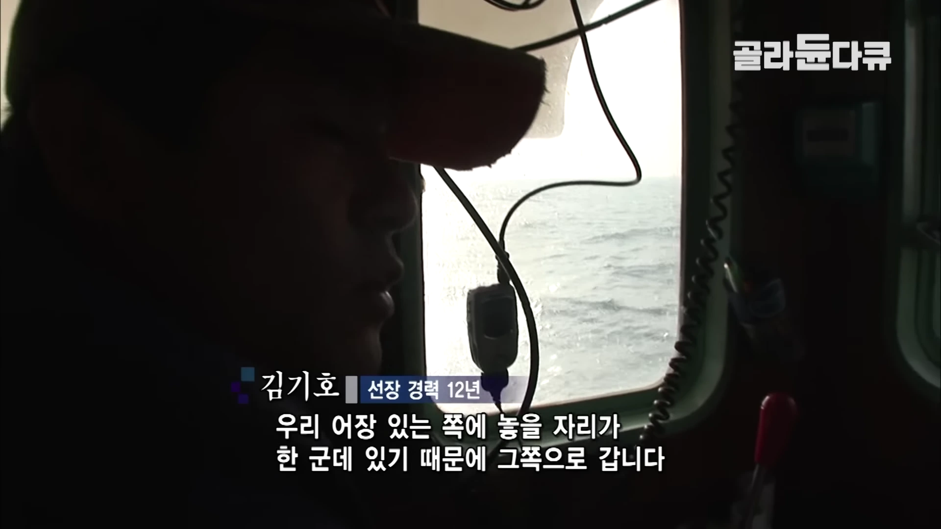 선상 조종실 안에서 창밖의 바다를 바라보며 운항 중인 선장의 옆모습이 보입니다.