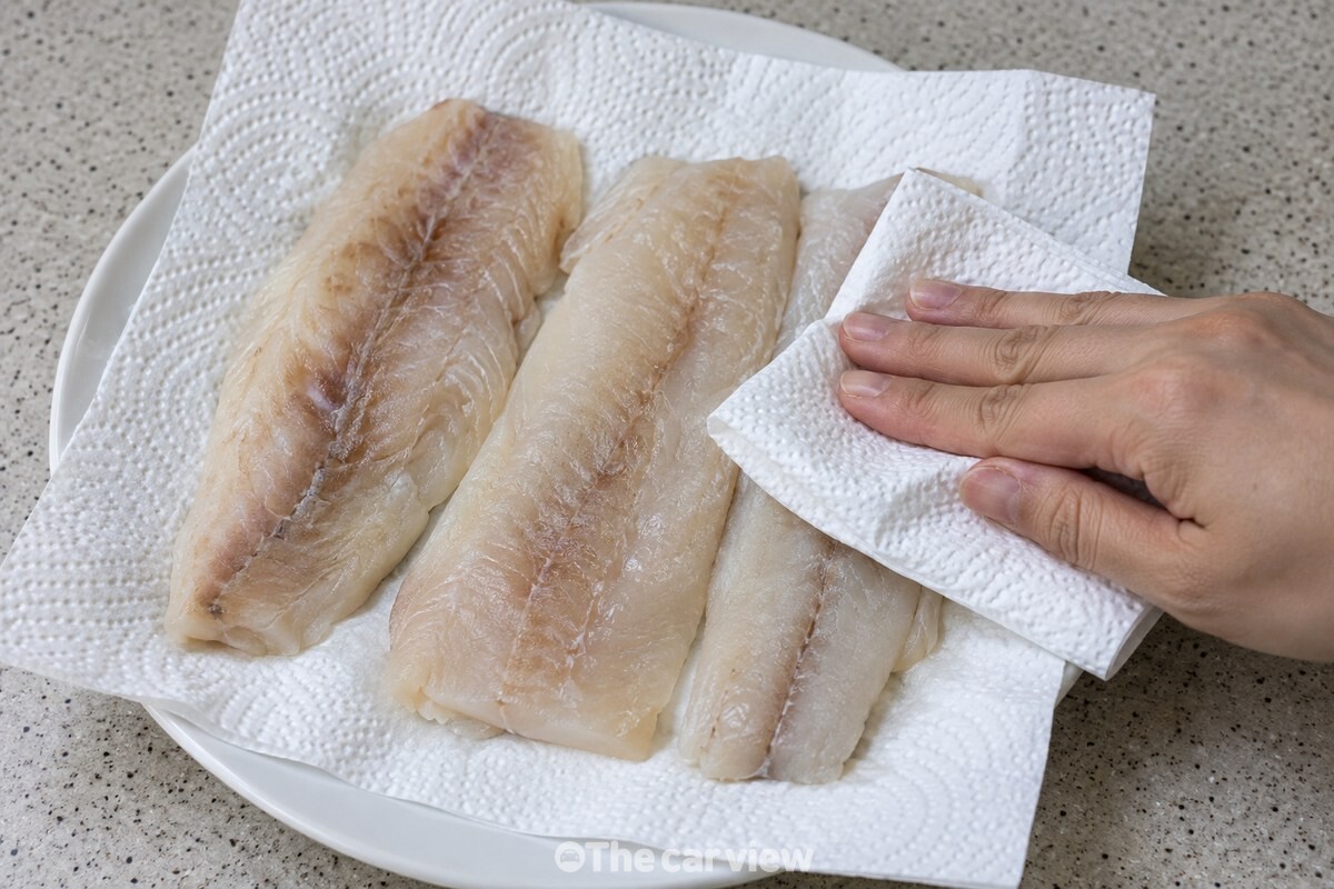 해동한 동태포를 키친타월 위에 펼쳐 표면 물기를 누르고 있다. / 기사 이해를 돕기 위한 생성형 이미지
