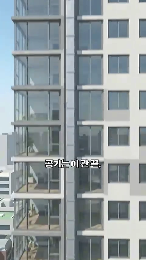 고층 아파트의 외벽을 수직으로 촬영한 모습으로 층마다 창문이 배치된 건물의 외관과 중앙의 수직 구조물이 보이며 영상 자막이 겹쳐져 있습니다.