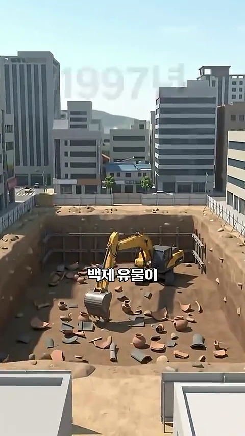도심 한복판 아파트 단지 공사 현장 깊은 흙 구덩이 속에 노란색 굴착기가 서 있고, 주변 바닥에는 깨진 도기 조각들과 토기 등 백제 유물들이 흩어져 있는 3D 애니메이션 스타일의 장면입니다.