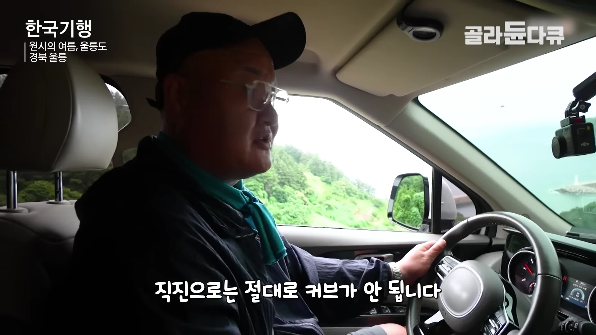 차량 운전석에 앉아 안경을 쓴 남성이 좁고 험한 길을 운전하며 설명하고 있는 모습
