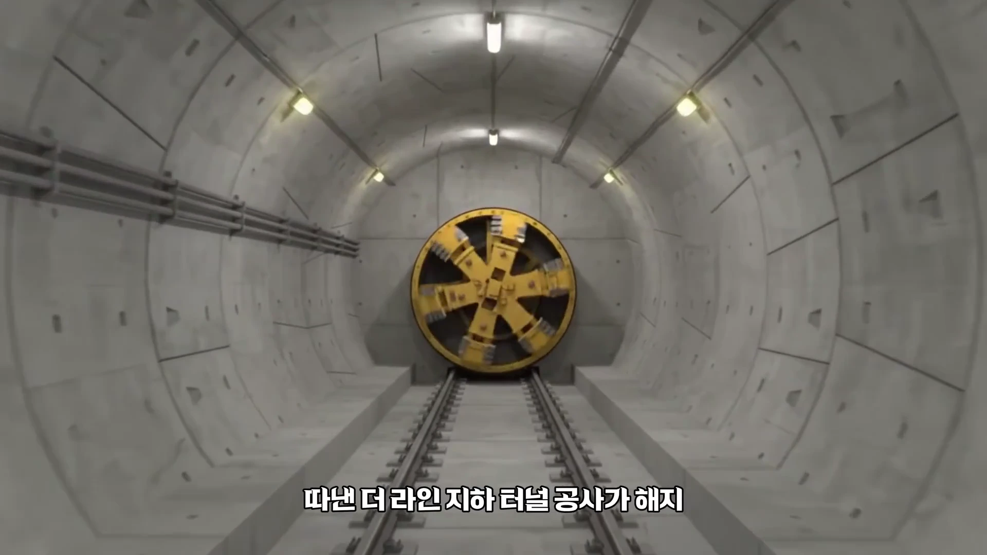 콘크리트로 마감된 원형 터널 내부 중앙에 노란색 원형 굴착 기계가 놓여 있고, 바닥에는 철로가 깔린 3D 그래픽 영상