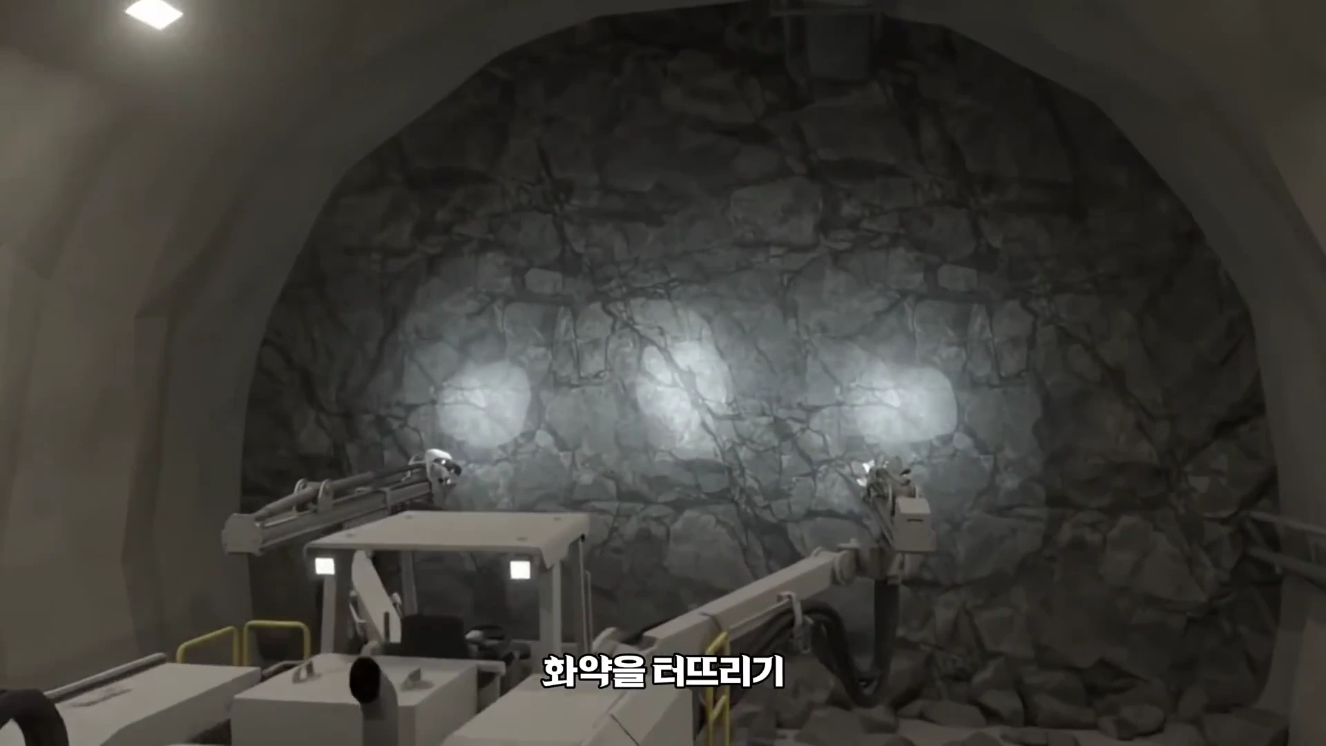터널 내부에서 굴착용 장비가 바위 벽면을 향해 빛을 비추고 있으며, 벽면에는 틈이 많은 암반의 모습이 보입니다.