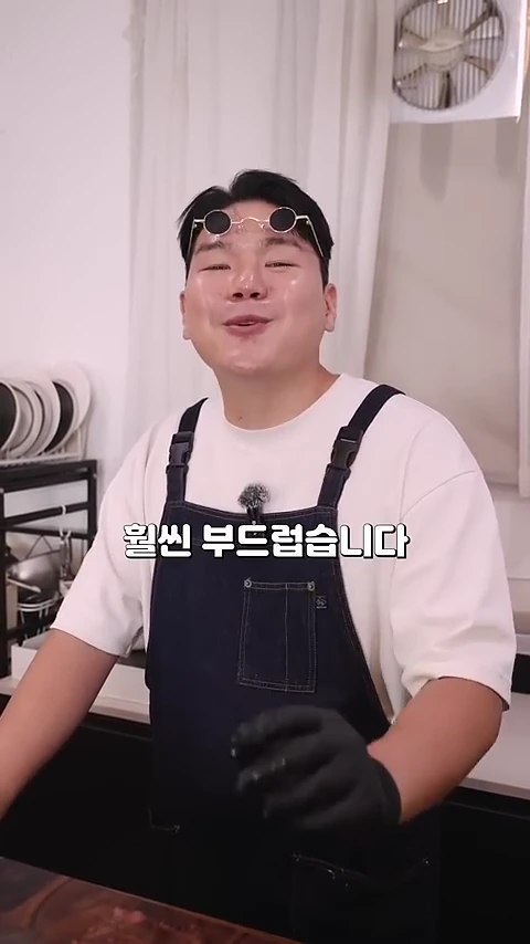 앞치마를 입고 검은색 장갑을 낀 남성이 카메라를 보며 이야기하고 있으며, 화면 중앙에는 '훨씬 부드럽습니다'라는 자막이 떠 있습니다.