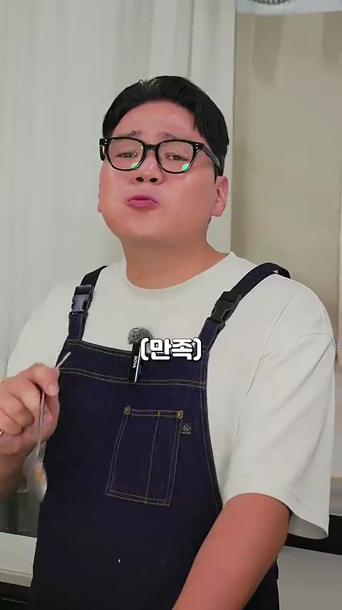 안경을 쓴 남성이 멜빵바지를 입고 조리된 고기를 맛본 뒤 만족스러운 표정을 짓고 있는 모습.
