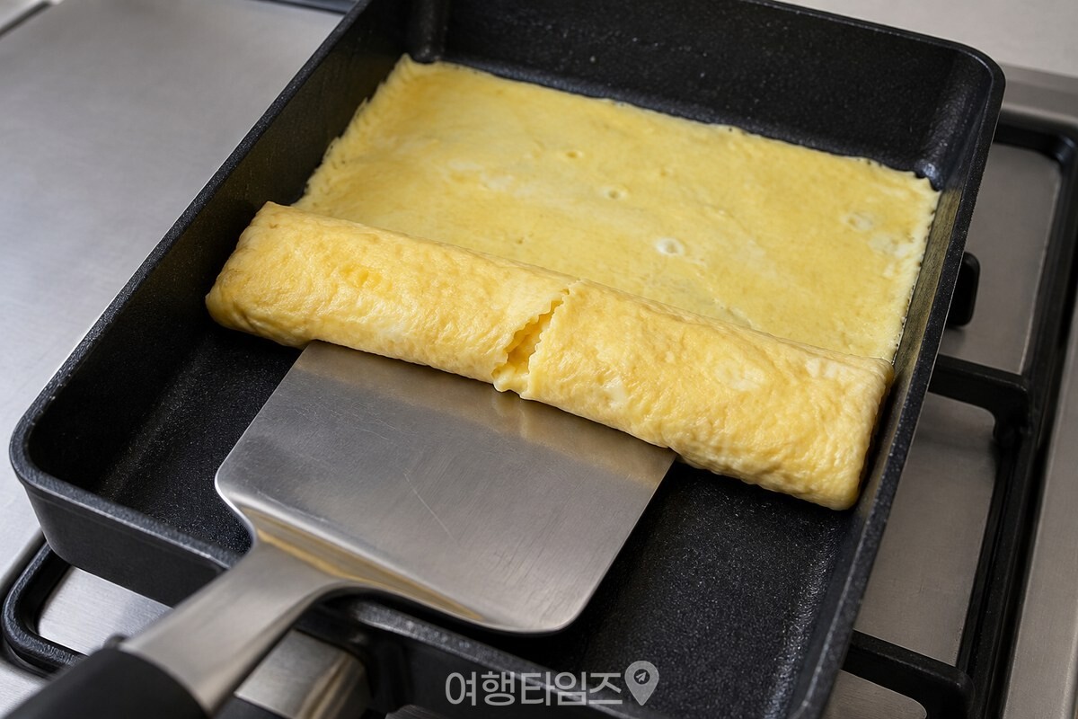 사각 팬에서 접히는 자리 한쪽이 갈라진 얇은 계란말이 / 기사 이해를 돕기 위한 생성형 이미지
