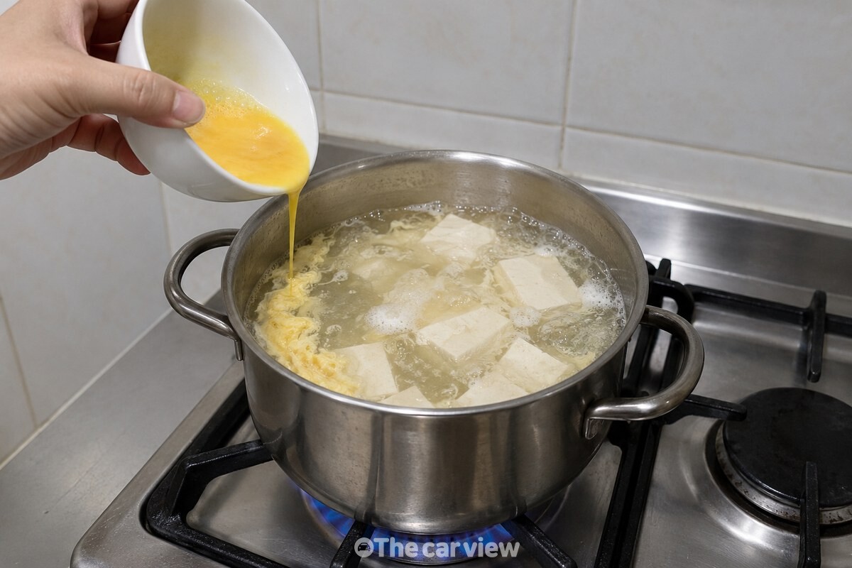 끓는 순두부 국물 가장자리로 풀어 둔 계란을 가늘게 붓는 모습 / 기사 이해를 돕기 위한 생성형 이미지
