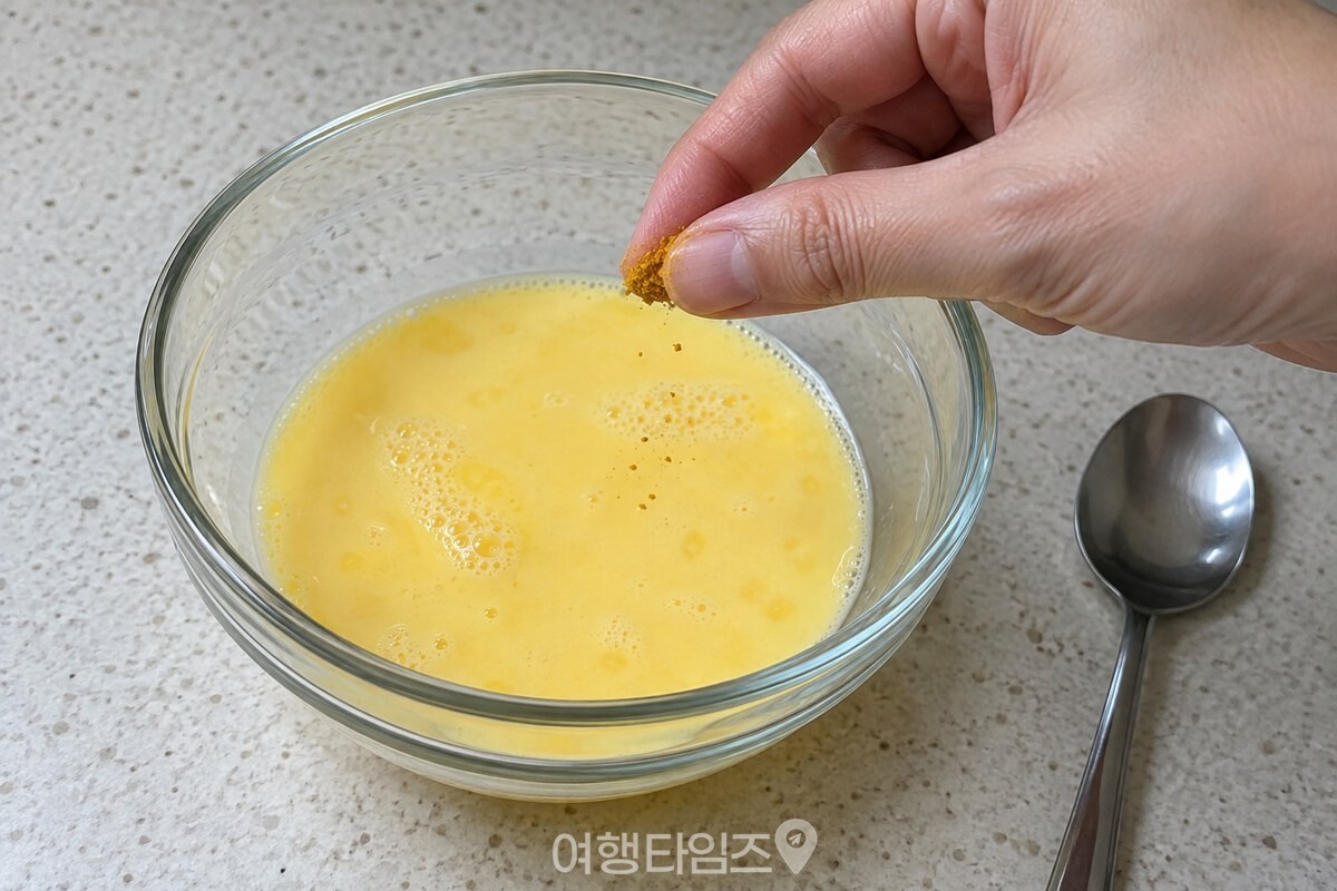 엄지와 집게손가락 끝에 묻은 소량의 카레가루를 계란물 위에 넣고 있다. / 기사 이해를 돕기 위한 생성형 이미지