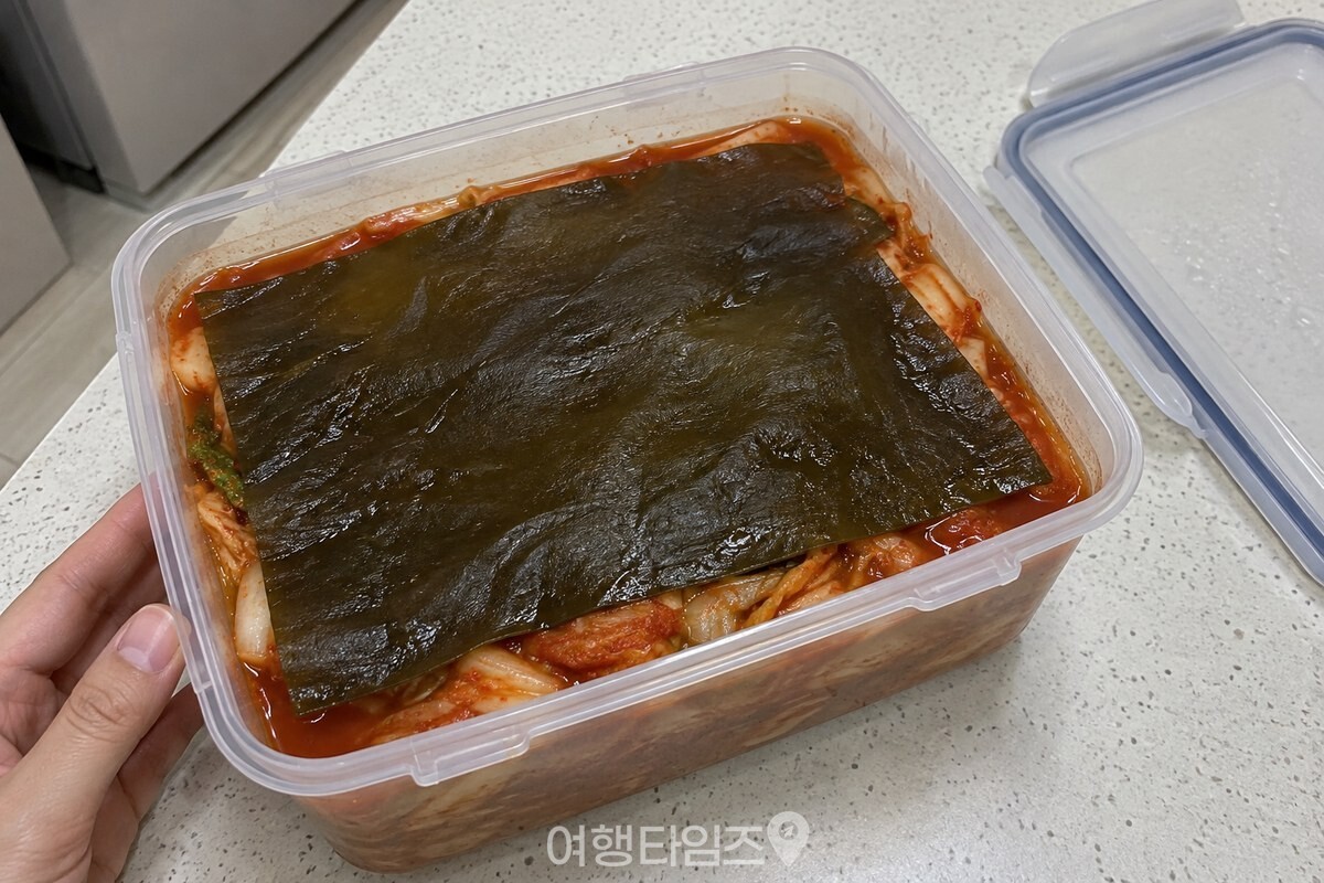 투명 김치통 안 김치 맨 위를 넓은 건다시마 한 장이 고르게 덮고 있다. / 기사 이해를 돕기 위한 생성형 이미지