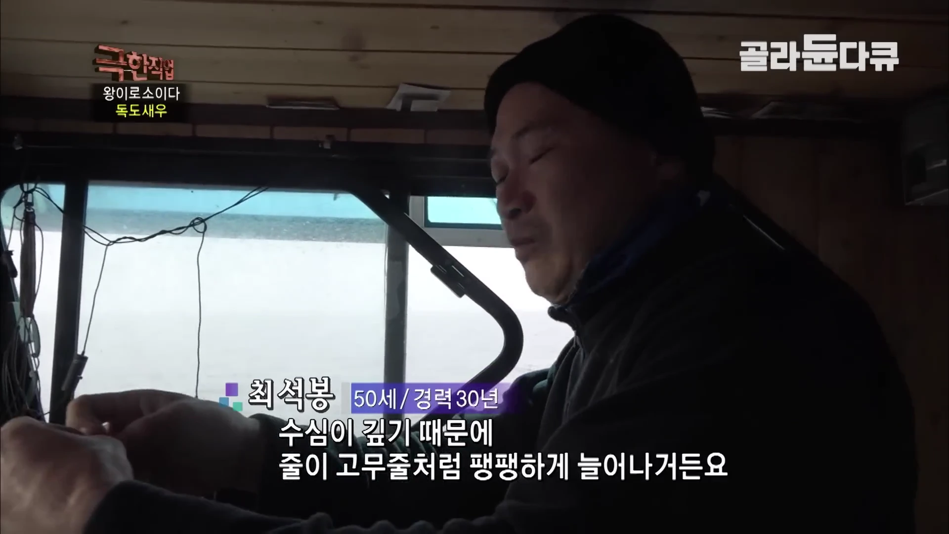 선상 조종실 안에서 검은색 모자와 점퍼를 입은 중년 남성이 진지한 표정으로 무언가를 설명하고 있으며, 화면 하단에는 '수심이 깊기 때문에 줄이 고무줄처럼 팽팽하게 늘어나거든요'라는 자막이 떠 있다.