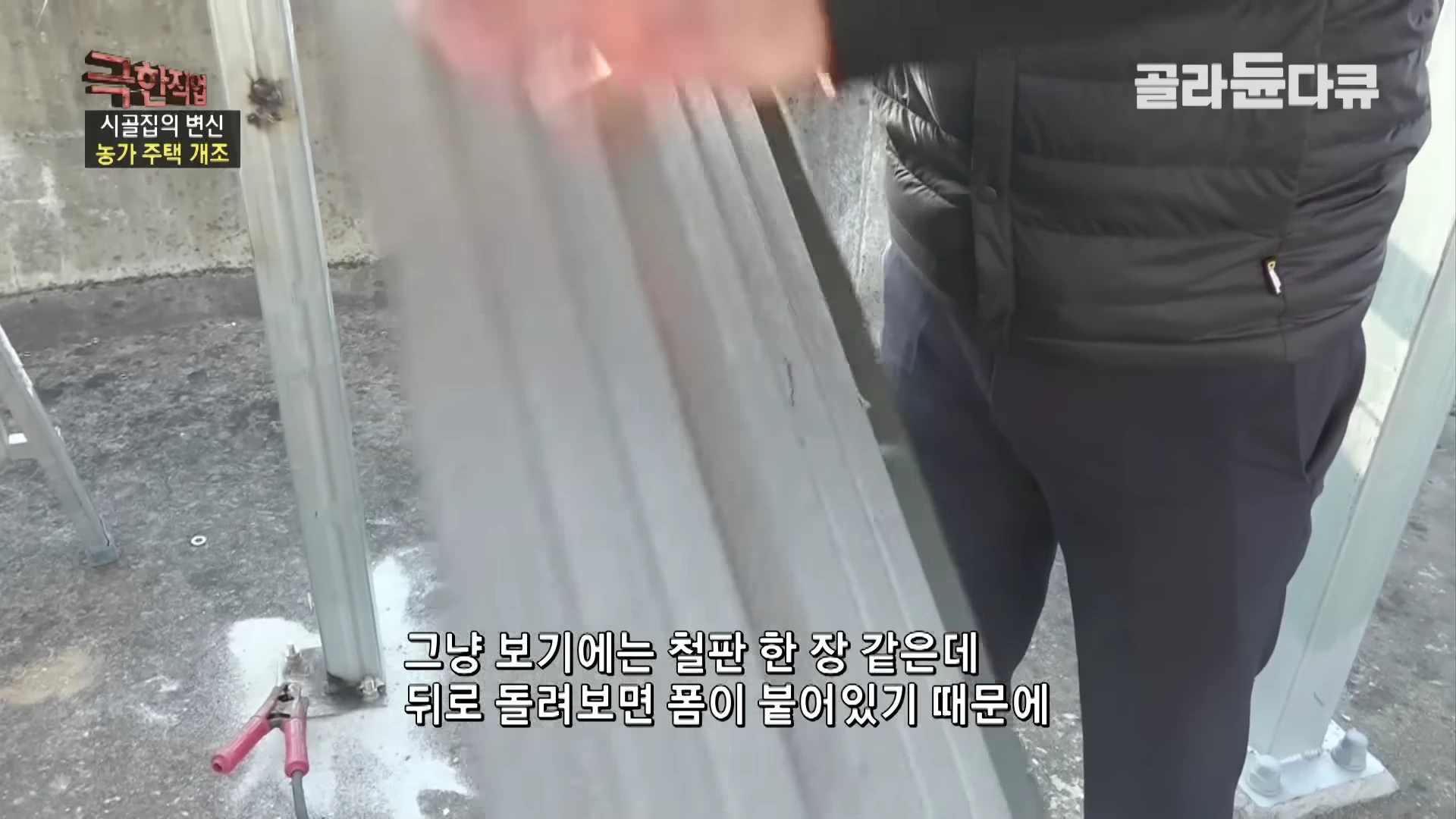 작업자가 손에 든 지붕 마감용 컬러 강판의 뒷면을 보여주고 있으며, 표면에는 단열재인 폼이 덧대어져 있다.