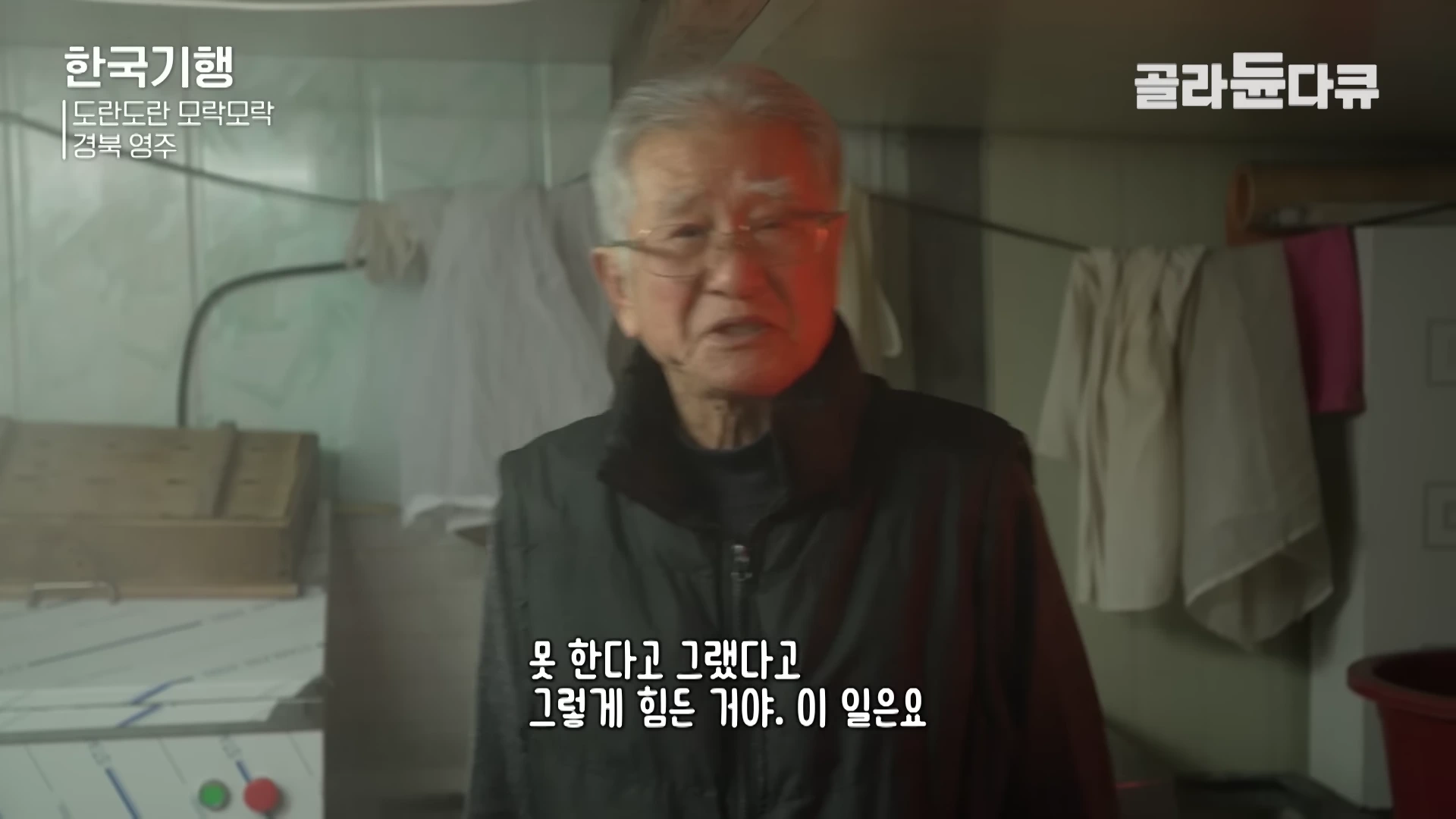 주방에서 흰머리가 지긋한 연세의 남성이 카메라를 보며 이야기를 나누고 있는 모습이 담긴 다큐멘터리 영상 화면이다.