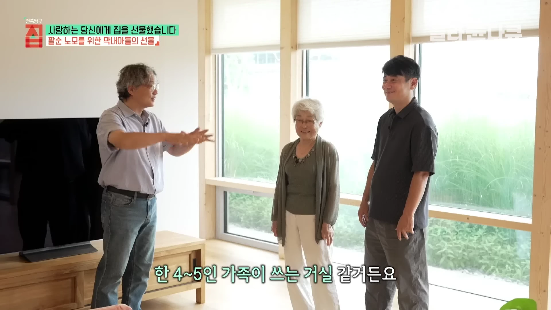 밝은 거실에서 중년의 남성과 연세 지긋한 여성, 그리고 안경을 쓴 남성이 서로 마주 보며 대화하고 있다.