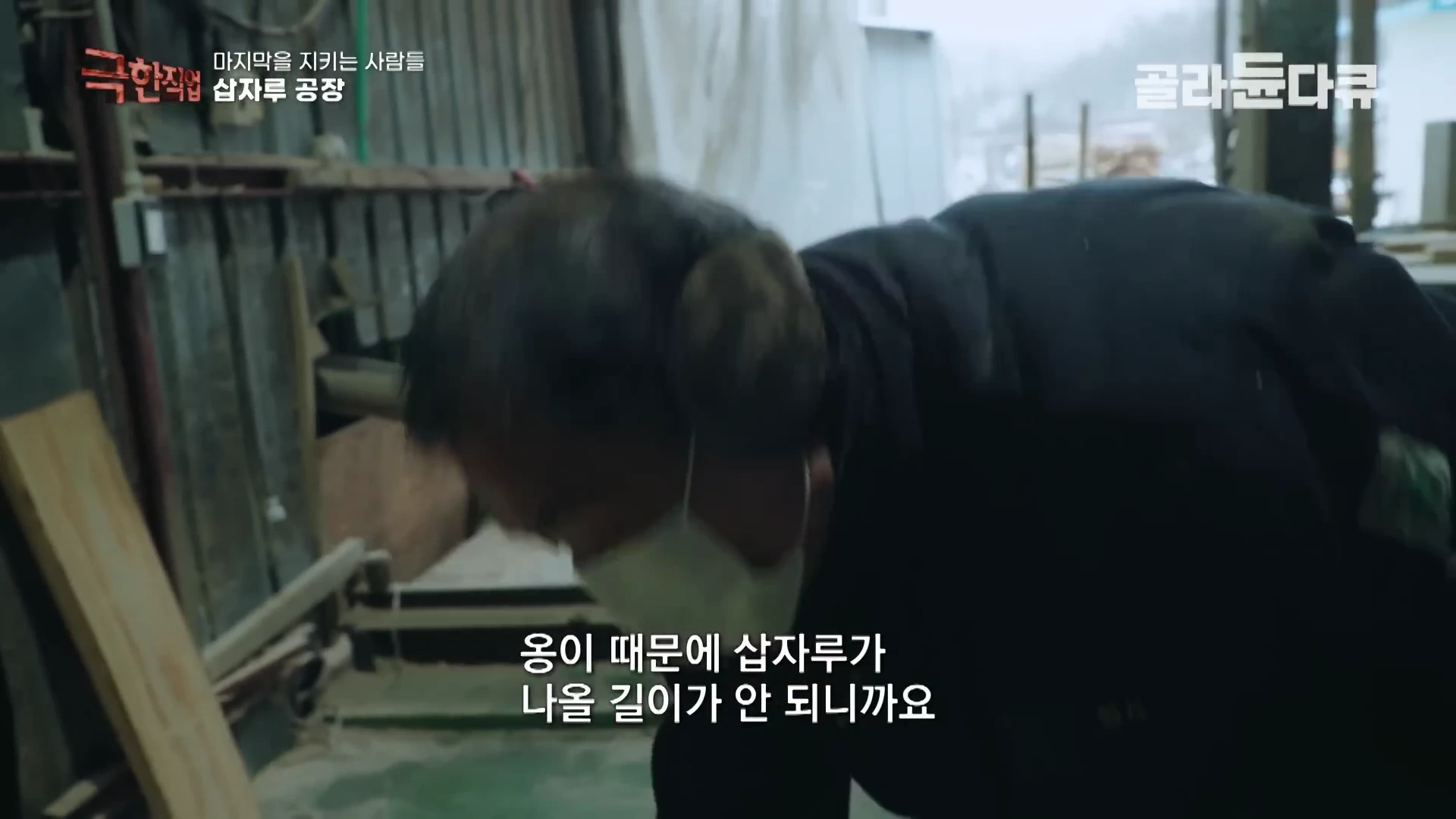 작업장에서 마스크와 귀마개를 착용한 작업자가 나무를 다듬고 있는 모습이 담긴 방송 화면