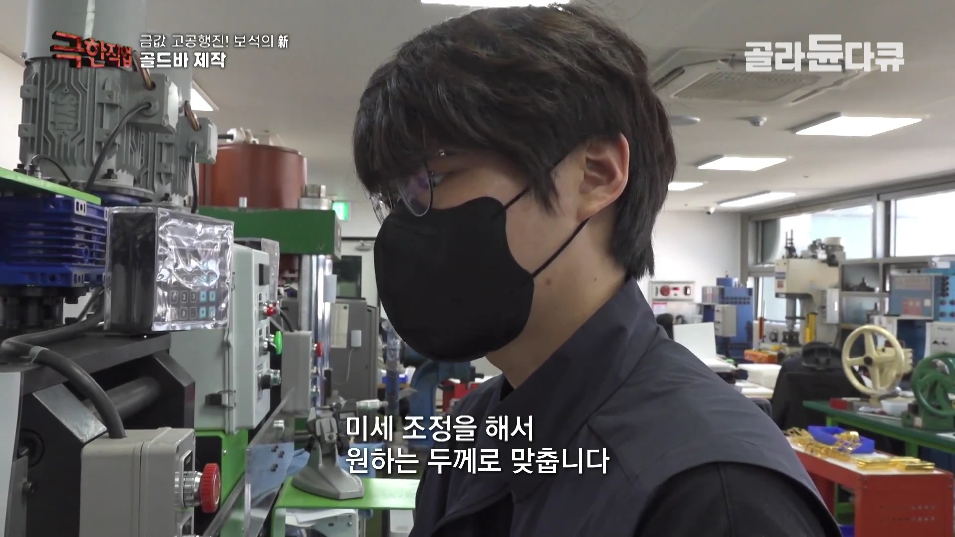 작업장에서 안경을 쓰고 마스크를 한 작업자가 압연기 앞에서 정밀한 작업을 진행하고 있는 모습