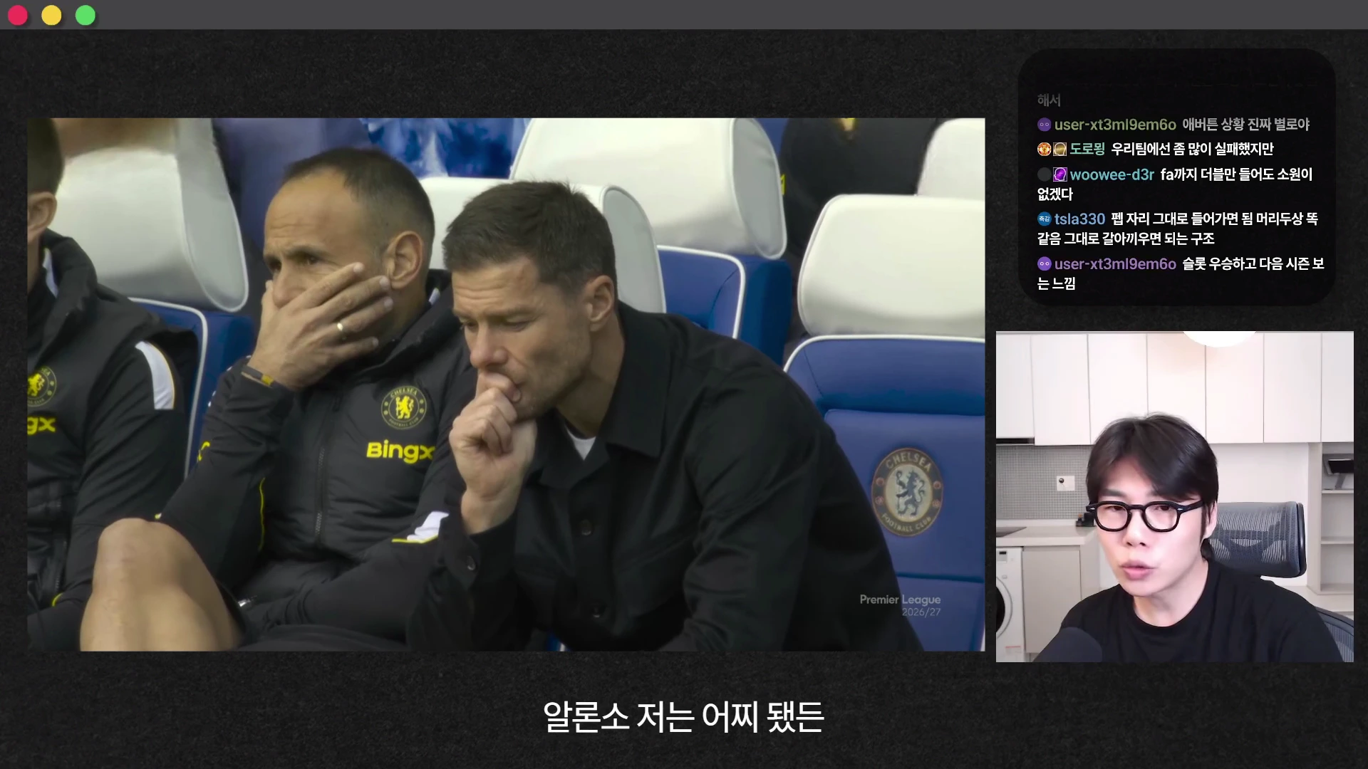 두 명의 남성이 경기장 벤치에 앉아 진지하게 경기를 지켜보고 있고, 오른쪽 하단에는 안경을 쓴 남성이 카메라를 보며 이야기하는 화면이 배치된 영상 캡처 이미지입니다.