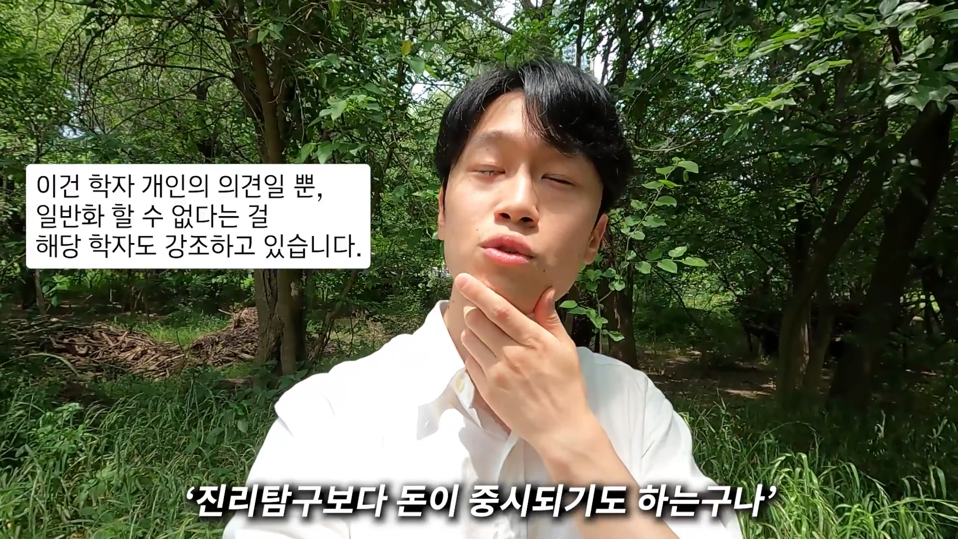 흰 셔츠를 입고 숲을 배경으로 서 있는 남성이 턱을 만지며 카메라를 보고 말하고 있으며 화면에는 자막이 삽입되어 있습니다.