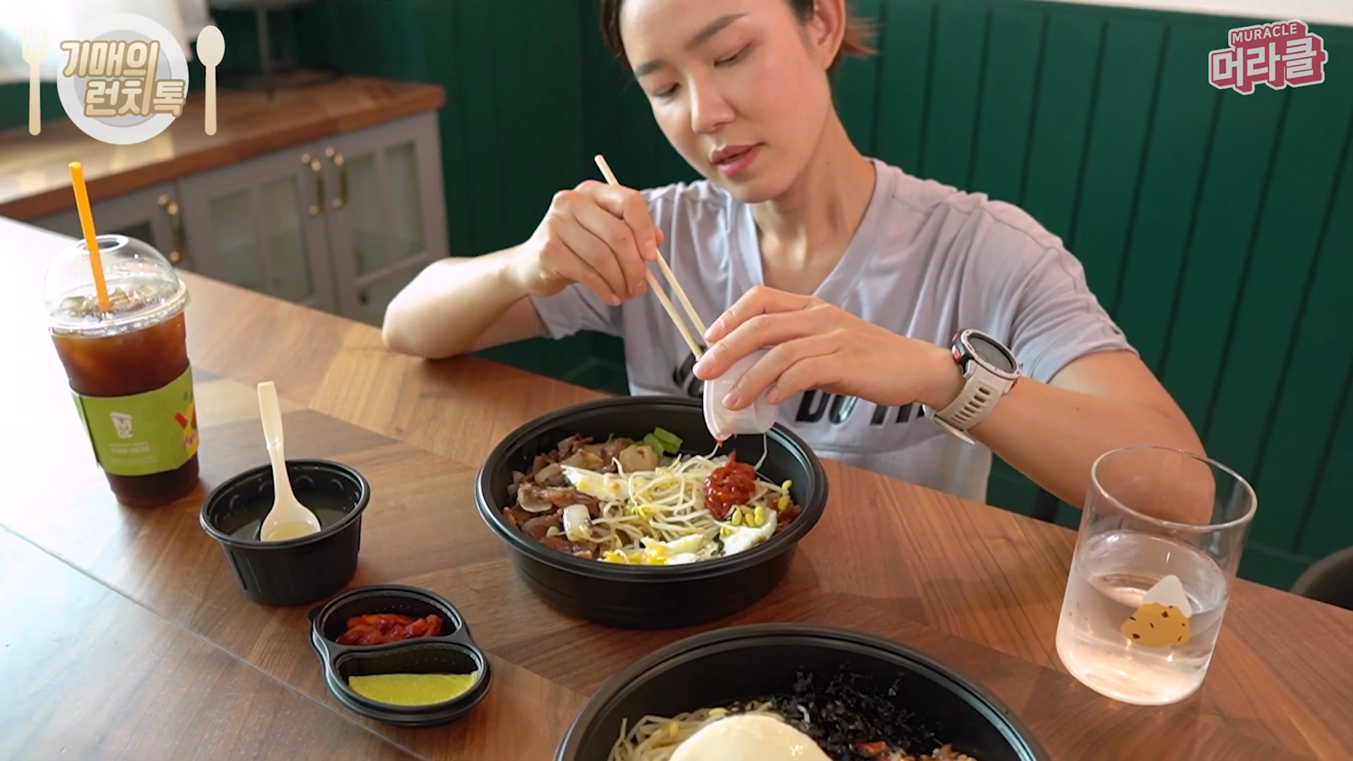 운동복 차림의 여성이 테이블에 앉아 비빔밥에 고추장을 넣고 있는 모습이 담긴 영상 캡처 화면입니다.