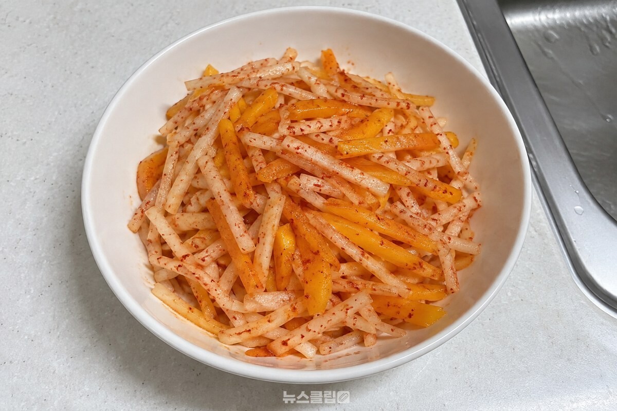 흰 그릇에 담긴 무 채와 단감 채가 가볍게 섞인 무생채 / 기사 이해를 돕기 위한 생성형 이미지