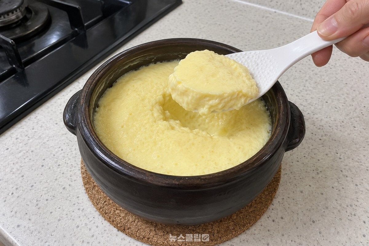 뚝배기 안에서 표면이 매끈하게 익은 계란찜을 흰 플라스틱 주걱으로 떠내는 모습. / 기사 이해를 돕기 위한 생성형 이미지