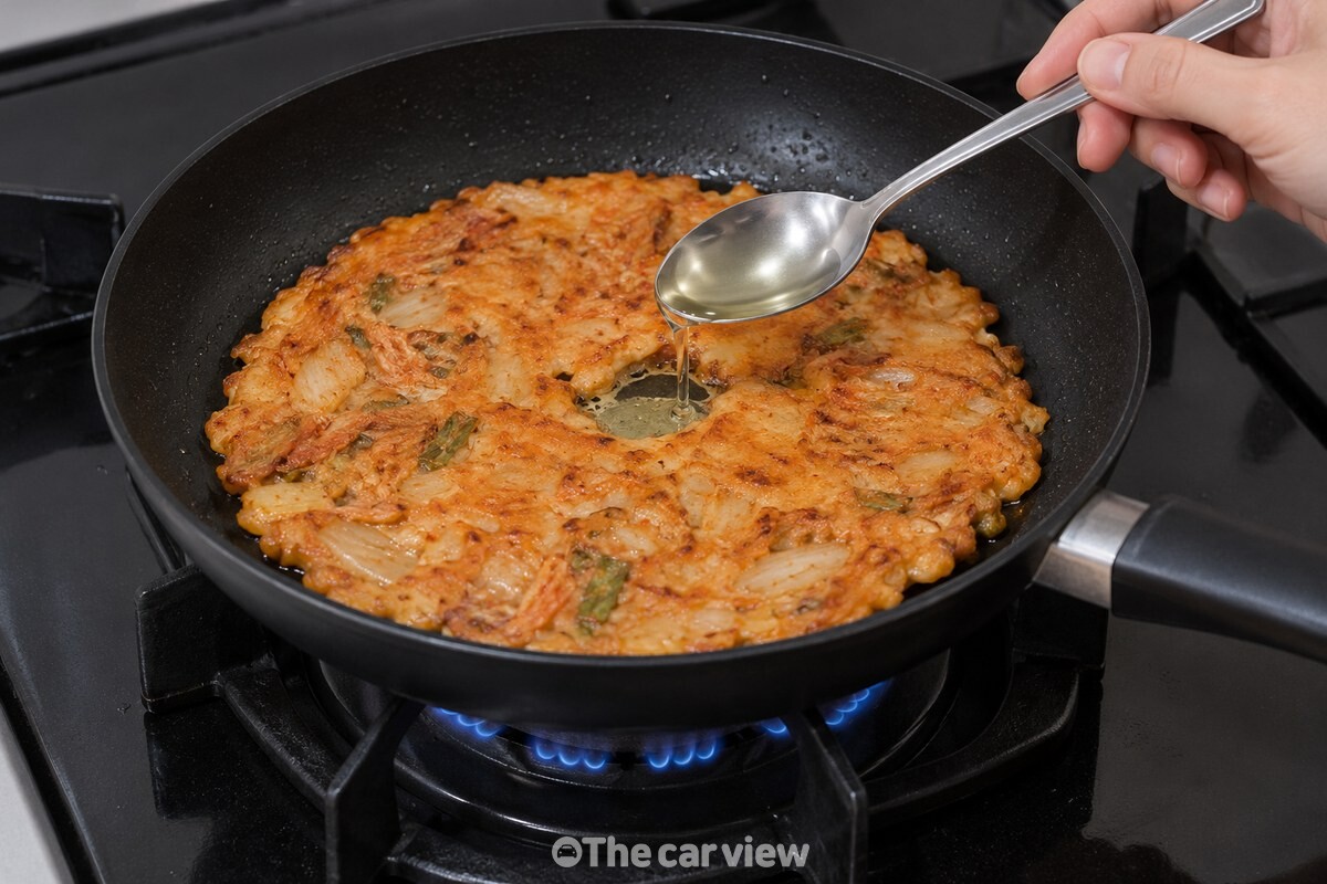 김치전 가운데의 작은 틈 가까이에 숟가락을 낮게 대고 식용유를 붓는 모습. / 기사 이해를 돕기 위한 생성형 이미지