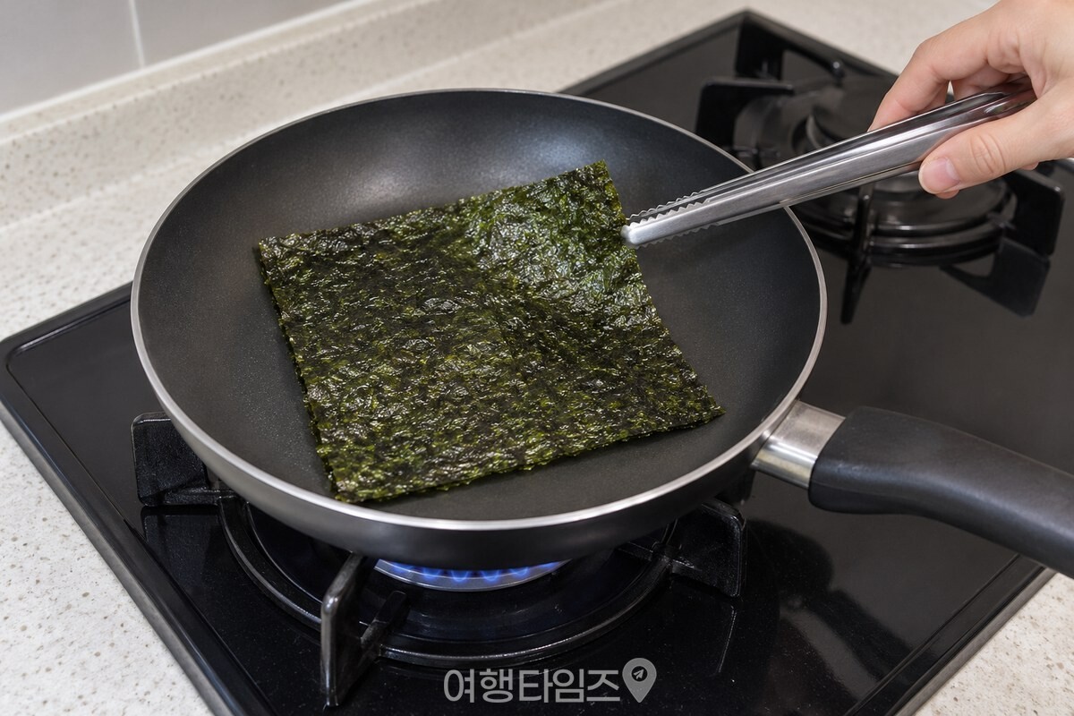 마른 팬에서 초록빛이 돌도록 살짝 구운 김을 집게로 뒤집는 모습. / 기사 이해를 돕기 위한 생성형 이미지