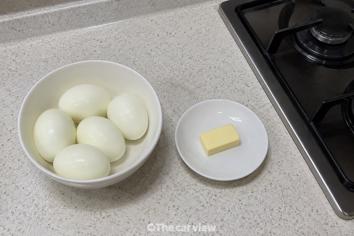 껍질을 깐 완숙 달걀과 버터를 팬 옆에 필요한 만큼 준비해 둔 모습이다. / 기사 이해를 돕기 위한 생성형 이미지