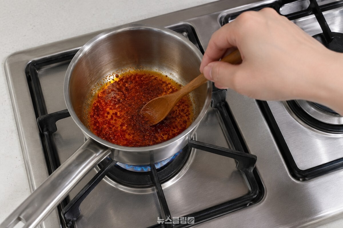 검은 주물 받침의 가스레인지 위 냄비에서 고춧가루를 짧게 볶아 붉어진 기름. / 기사 이해를 돕기 위한 생성형 이미지