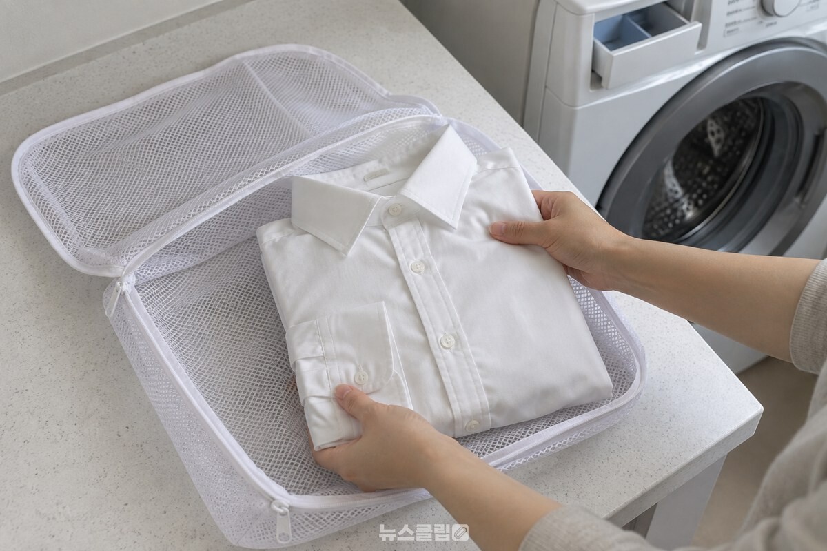 단추를 잠그고 소매를 접은 와이셔츠 한 장을 네모난 세탁망 바닥 크기에 맞춰 넣고 있다. / 기사 이해를 돕기 위한 생성형 이미지