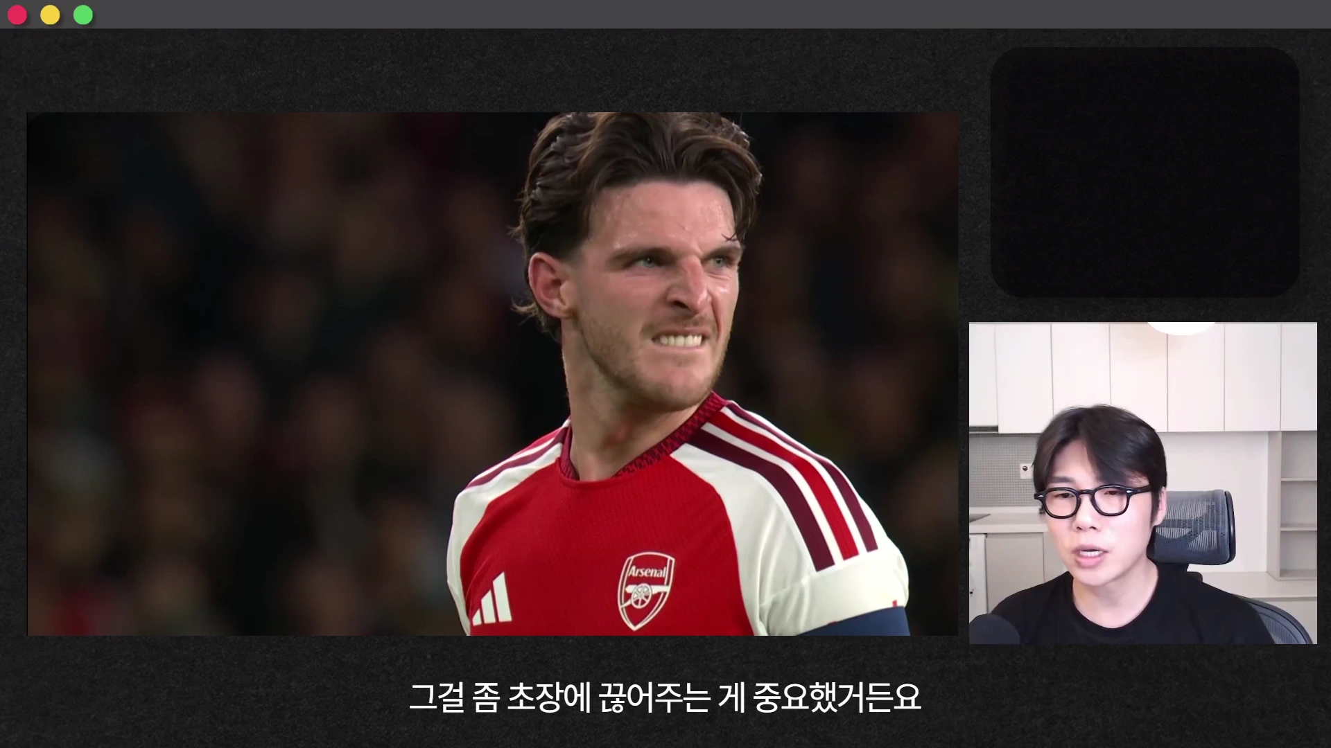 붉은색과 흰색이 섞인 축구 유니폼을 입고 얼굴을 찡그린 선수와 오른쪽에 안경을 쓴 남성이 마이크 앞에서 이야기하고 있는 화면