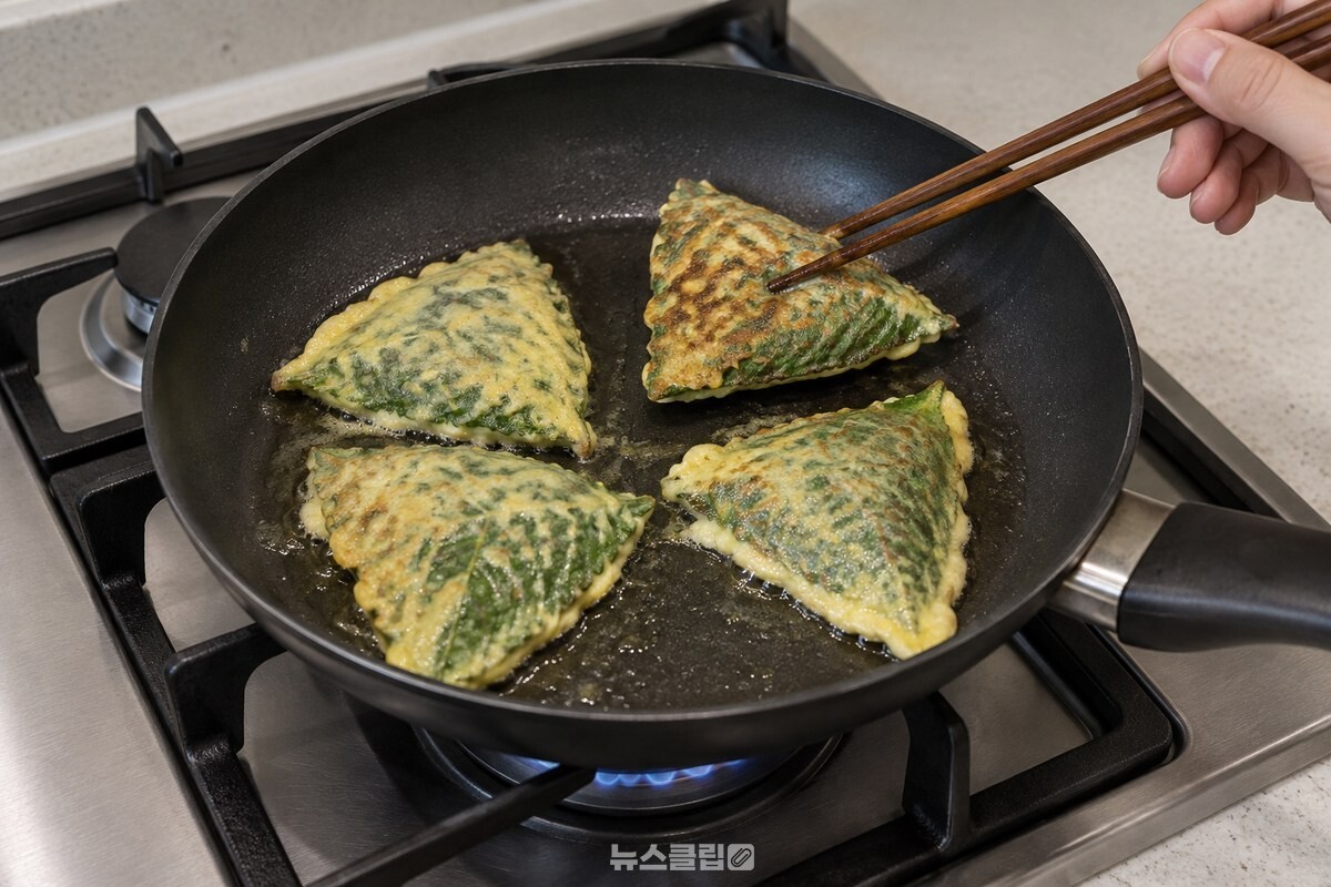 검은 프라이팬에서 접힌 부분을 아래로 둔 깻잎전을 중불에 굽는 모습. / 기사 이해를 돕기 위한 생성형 이미지