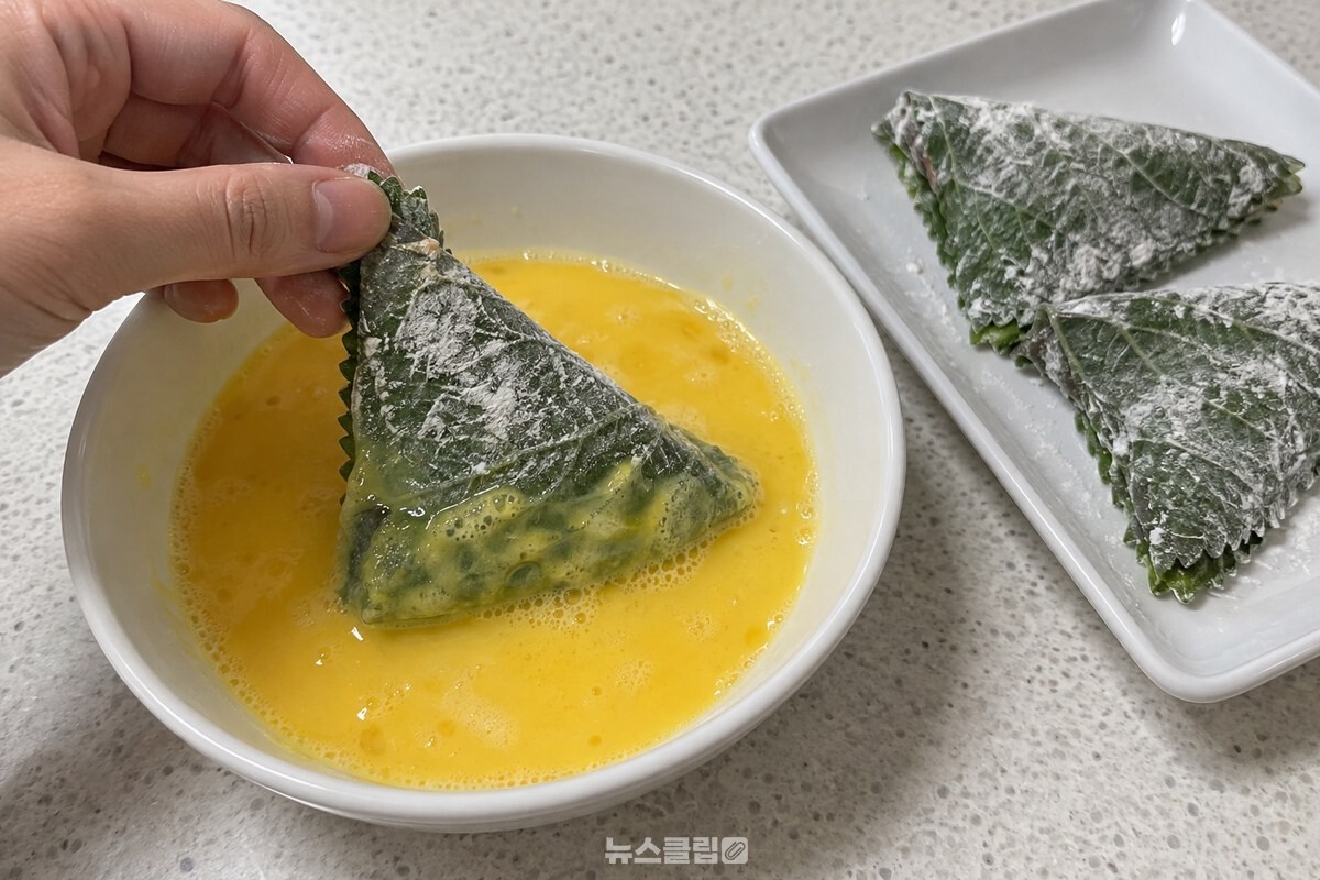 삼각형으로 접은 깻잎전을 풀어 둔 달걀물에 적셔 달걀옷을 입히는 모습. / 기사 이해를 돕기 위한 생성형 이미지