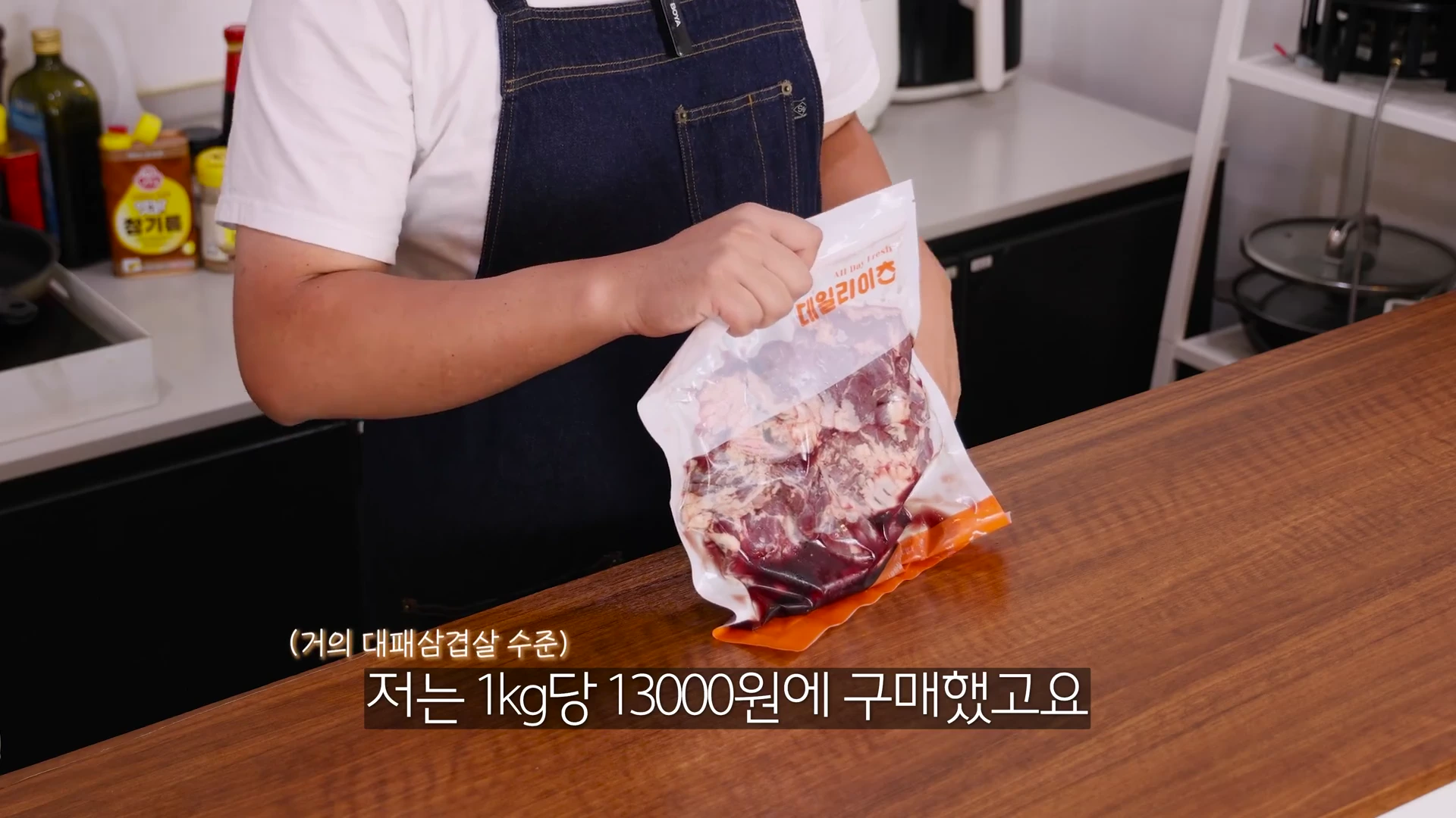 앞치마를 두른 남성이 진공 포장된 갈매기살 팩을 양손으로 들고 있는 모습.