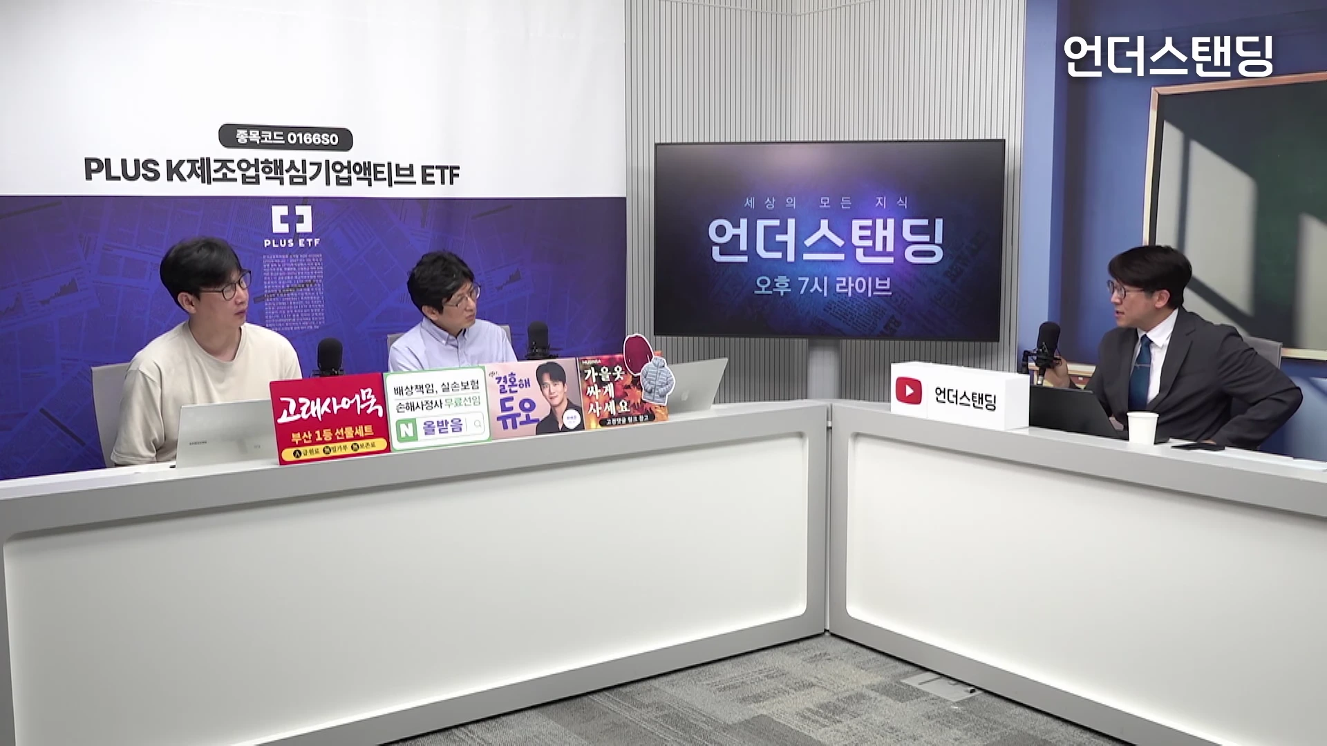 두 명의 출연자와 한 명의 진행자가 마이크가 설치된 흰색 테이블에 앉아 대화를 나누고 있는 스튜디오의 모습.