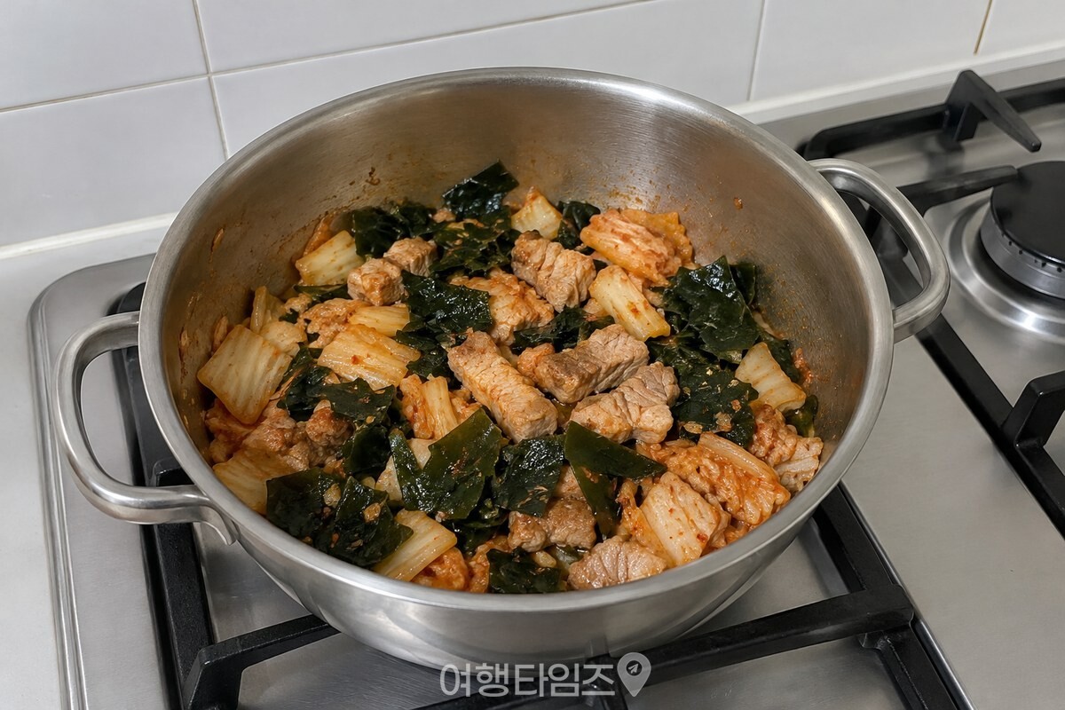 볶는 단계에서 김치와 돼지고기에 잘게 썬 미역을 넣은 냄비. / 기사 이해를 돕기 위한 생성형 이미지