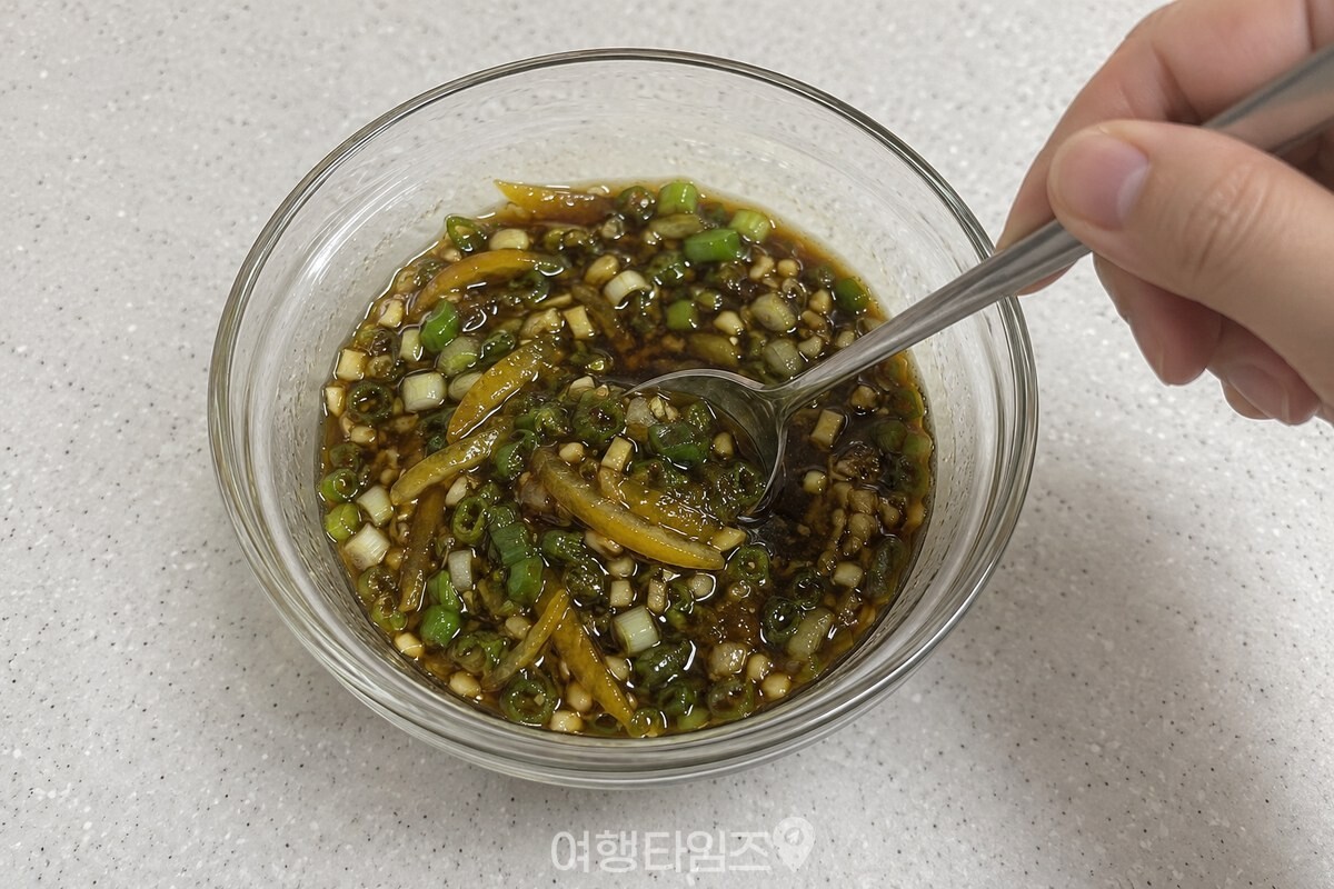 유자 껍질 조각이 든 유자청과 간장을 작은 유리 그릇에 섞고 있다. / 기사 이해를 돕기 위한 생성형 이미지