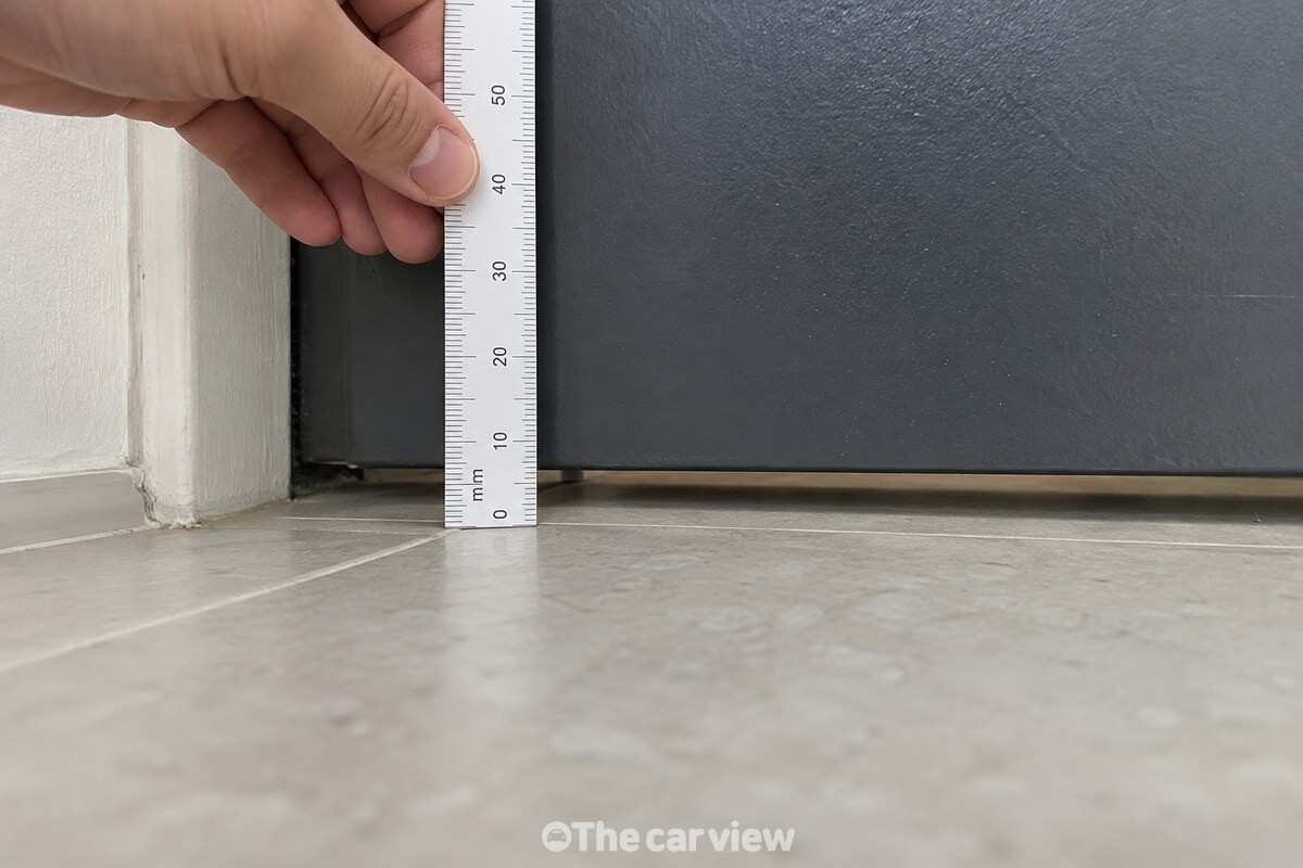 닫힌 현관문 아래에 5~15mm 정도 남은 바닥 틈을 자와 함께 확인하는 모습. / 기사 이해를 돕기 위한 생성형 이미지