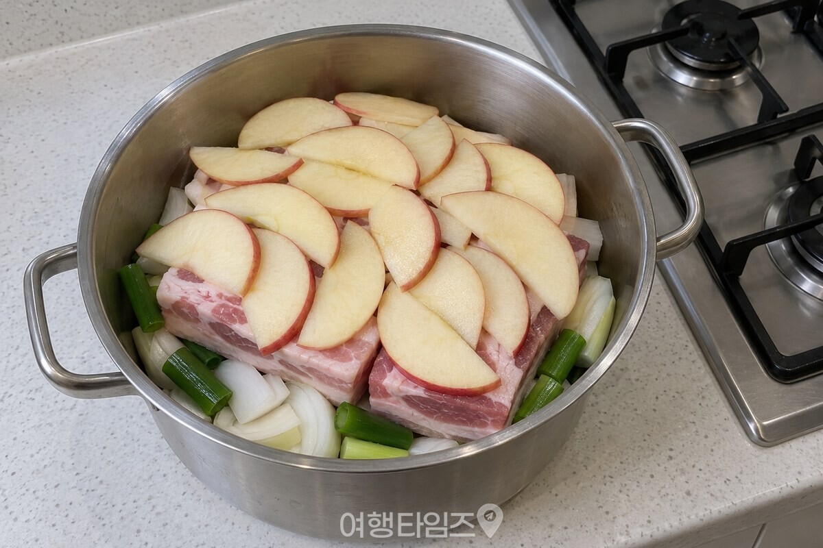 두툼하게 썬 삼겹살 위를 얇은 사과 조각이 겹쳐 덮은 냄비 모습. / 기사 이해를 돕기 위한 생성형 이미지