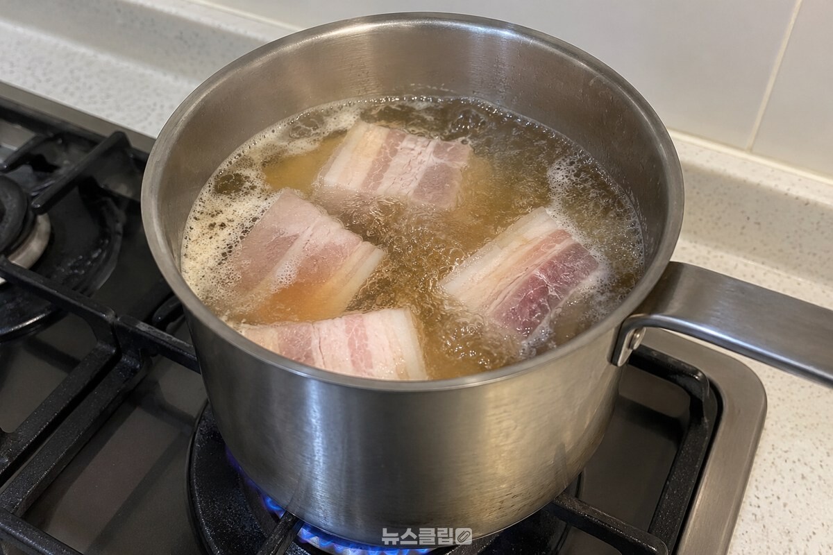 끓는 맥주가 담긴 작은 냄비에서 두툼한 돼지고기 조각을 삶는 모습. / 기사 이해를 돕기 위한 생성형 이미지